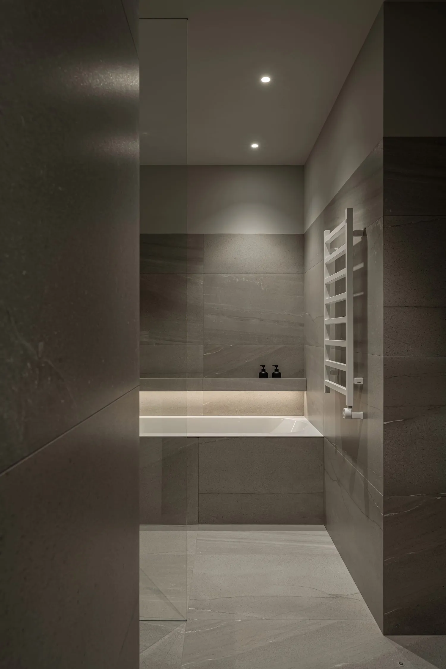 Modern bathroom designed with concrete tiles, featuring warm lighting and minimalist decor.