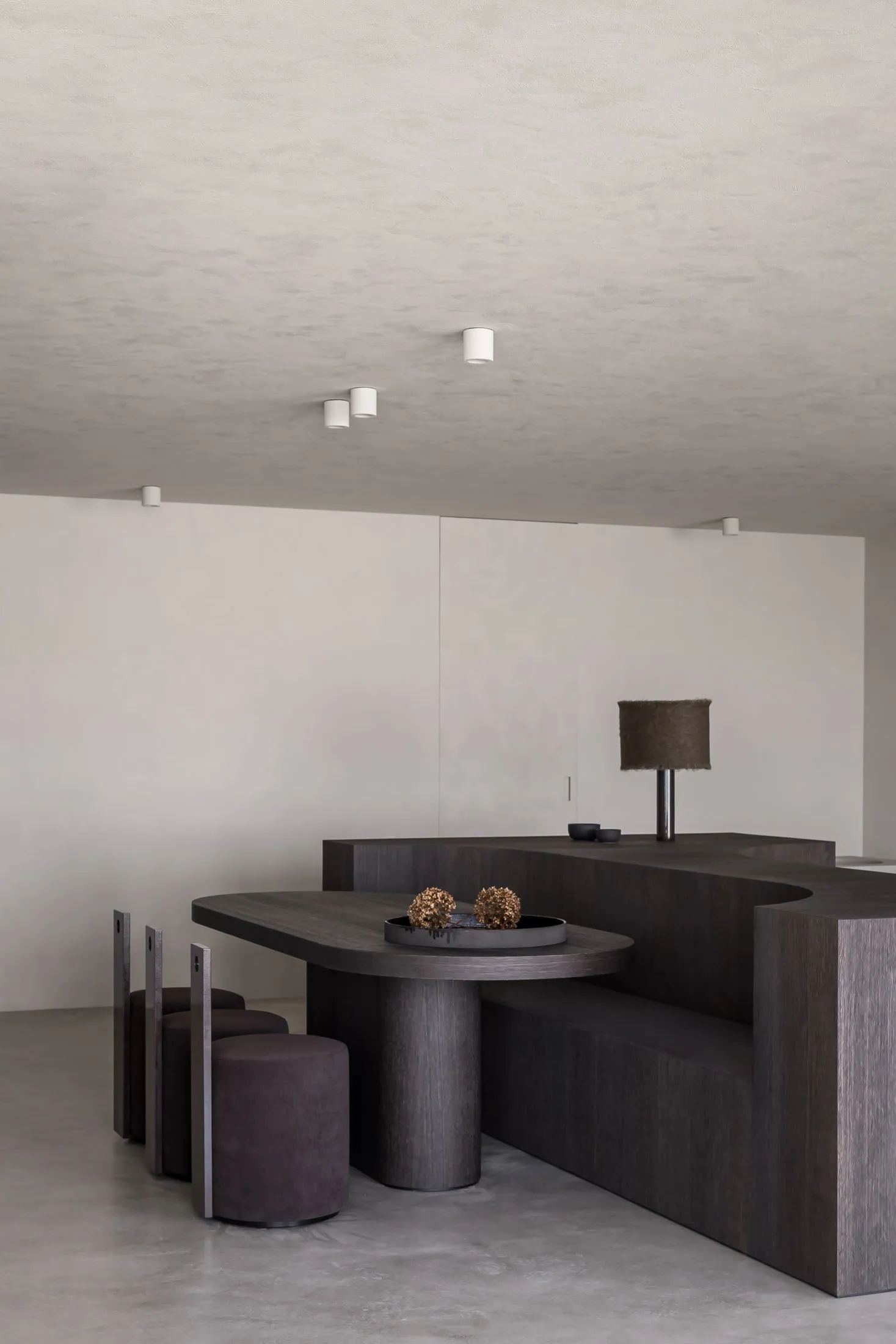A modern dining room featuring minimalist design elements, including a wooden dining table, gray concrete stairs, and a sleek