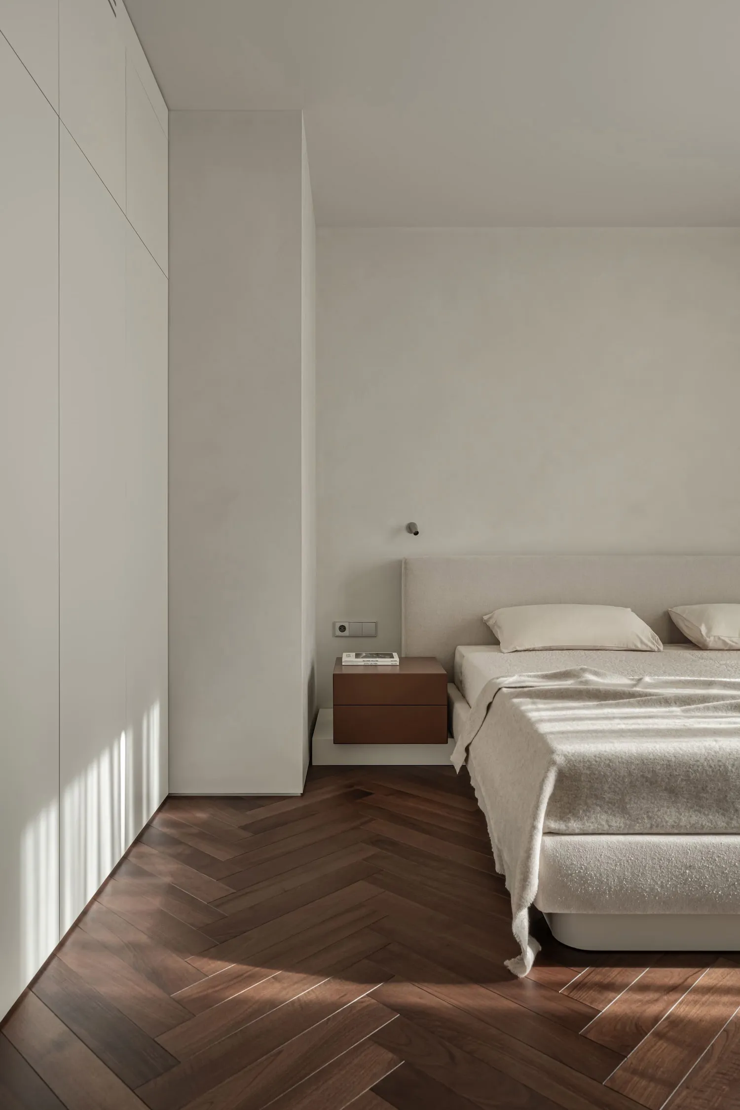 A minimalist bedroom with a bed, floating nightstand, and simple decor in neutral tones.