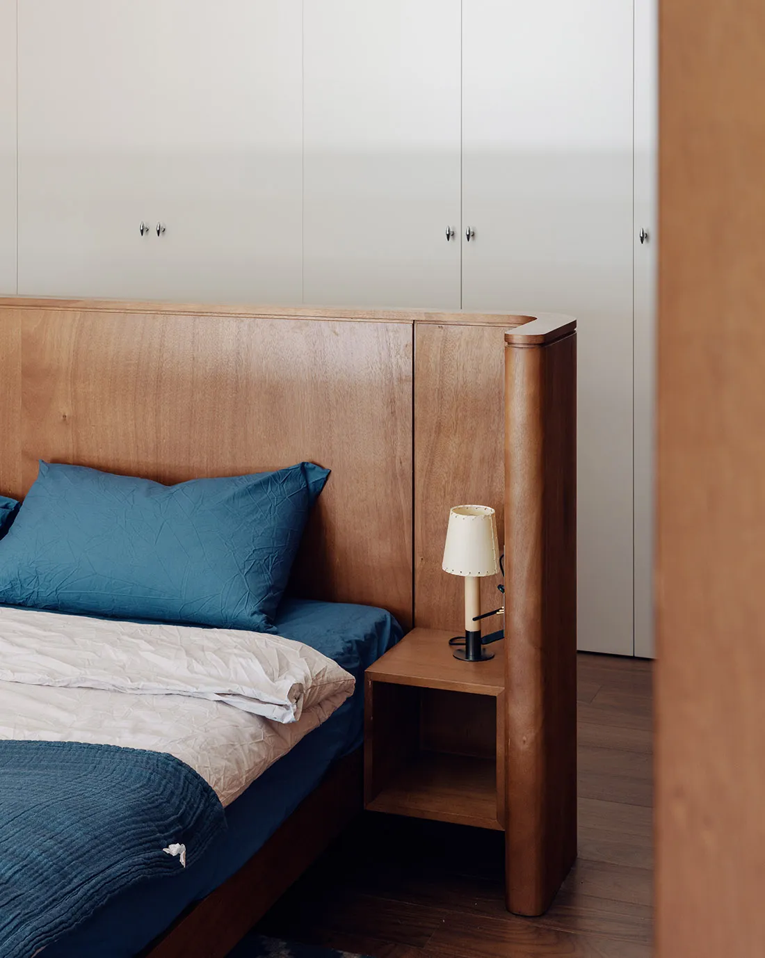 Minimalist bedroom with a wooden headboard and blue bedding.