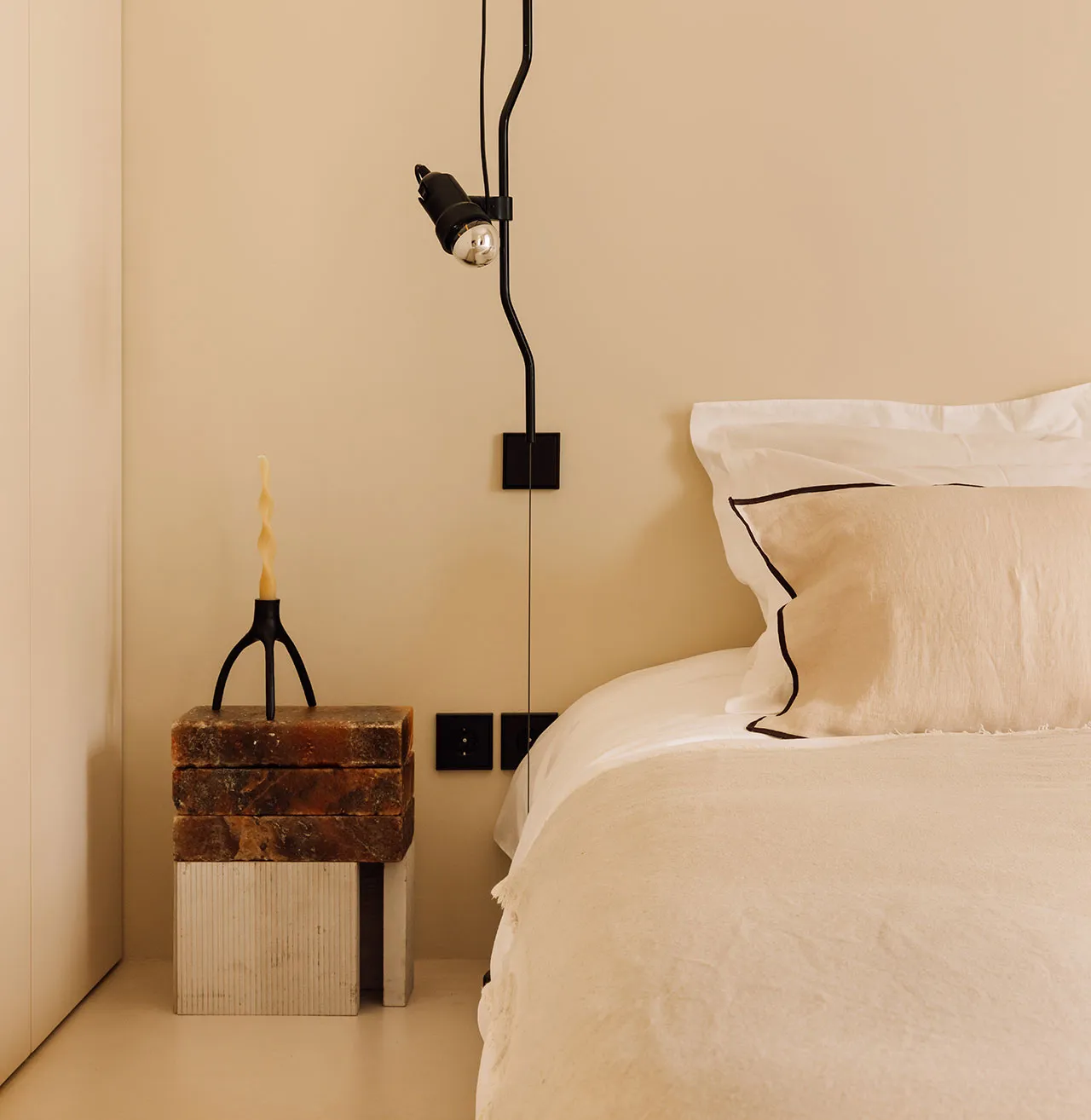 A modern bedroom with neutral tones, minimalist design, and a cozy atmosphere. Includes a bed with white bedding, a stone nig