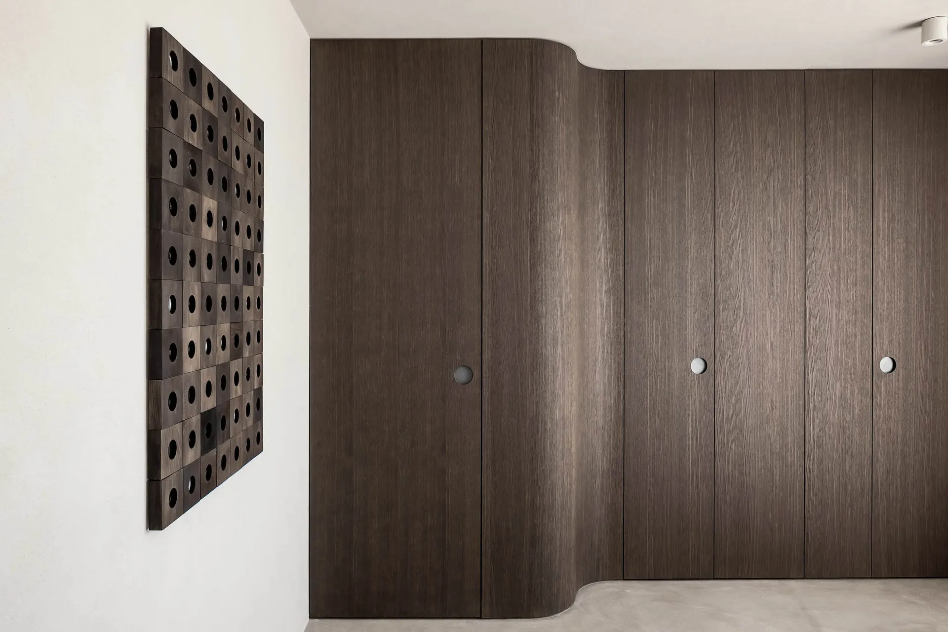 Modern wooden cabinets with patterned wall art on a white wall