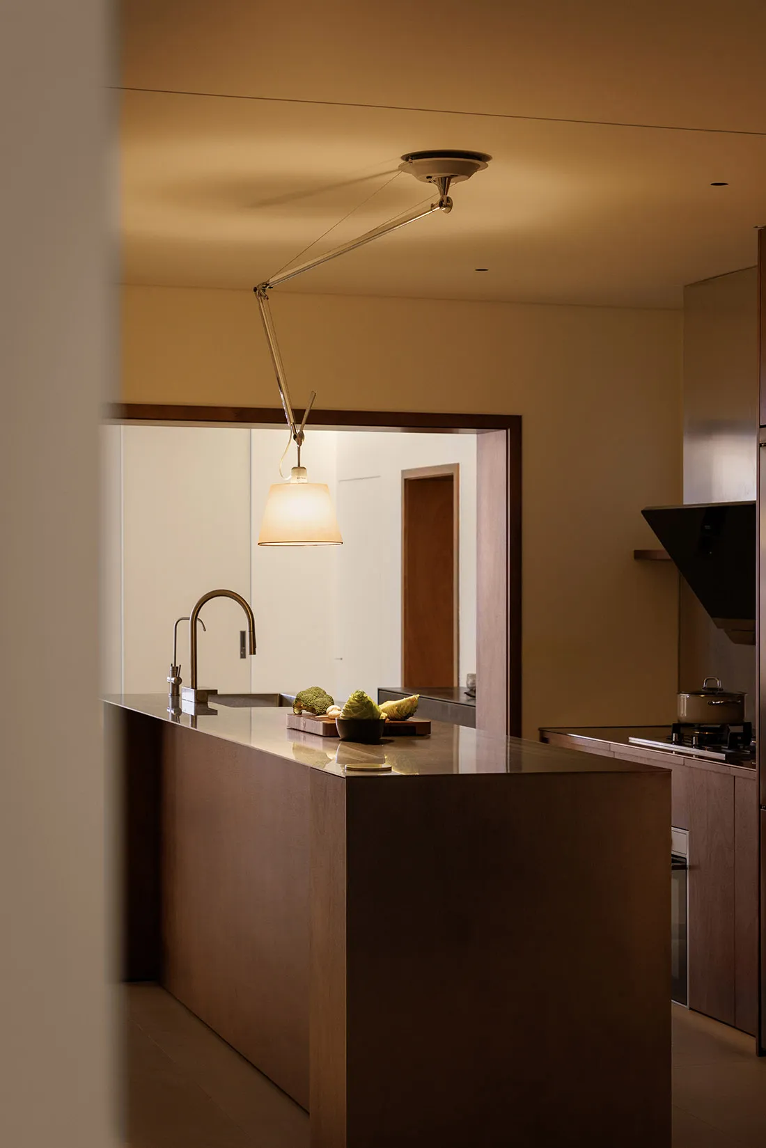 A modern, minimalist kitchen with a wooden countertop, featuring a variety of fruits on a cutting board.