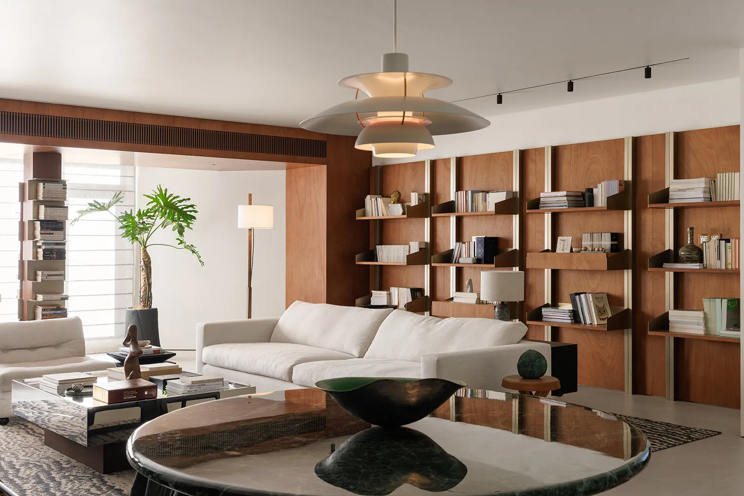 A modern living room with a marble coffee table, white sofa, and wooden shelves.