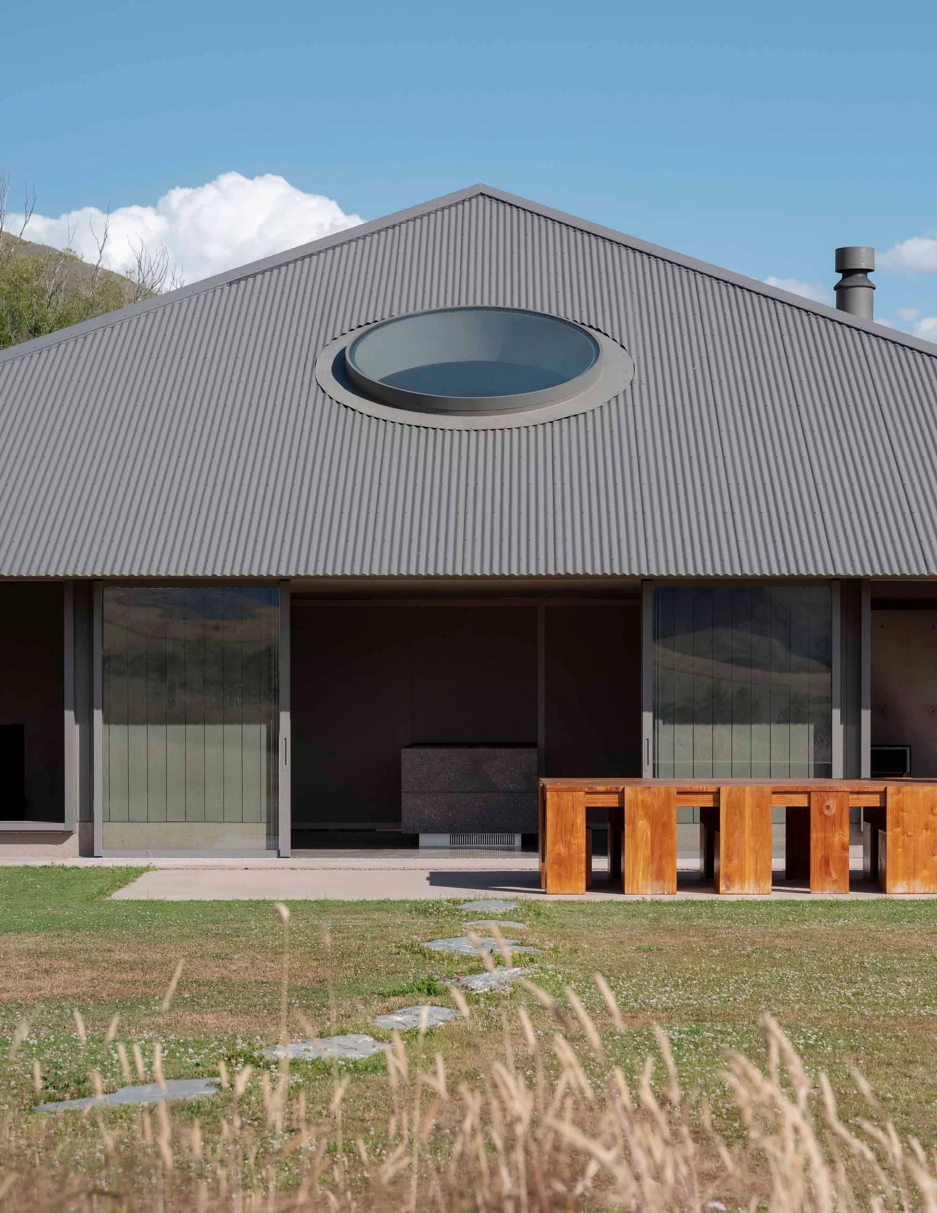 Modern residential home with metallic roof and large glass windows.