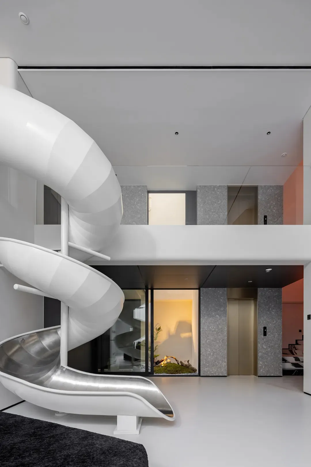 A modern interior space featuring a white metal slide and a concrete wall