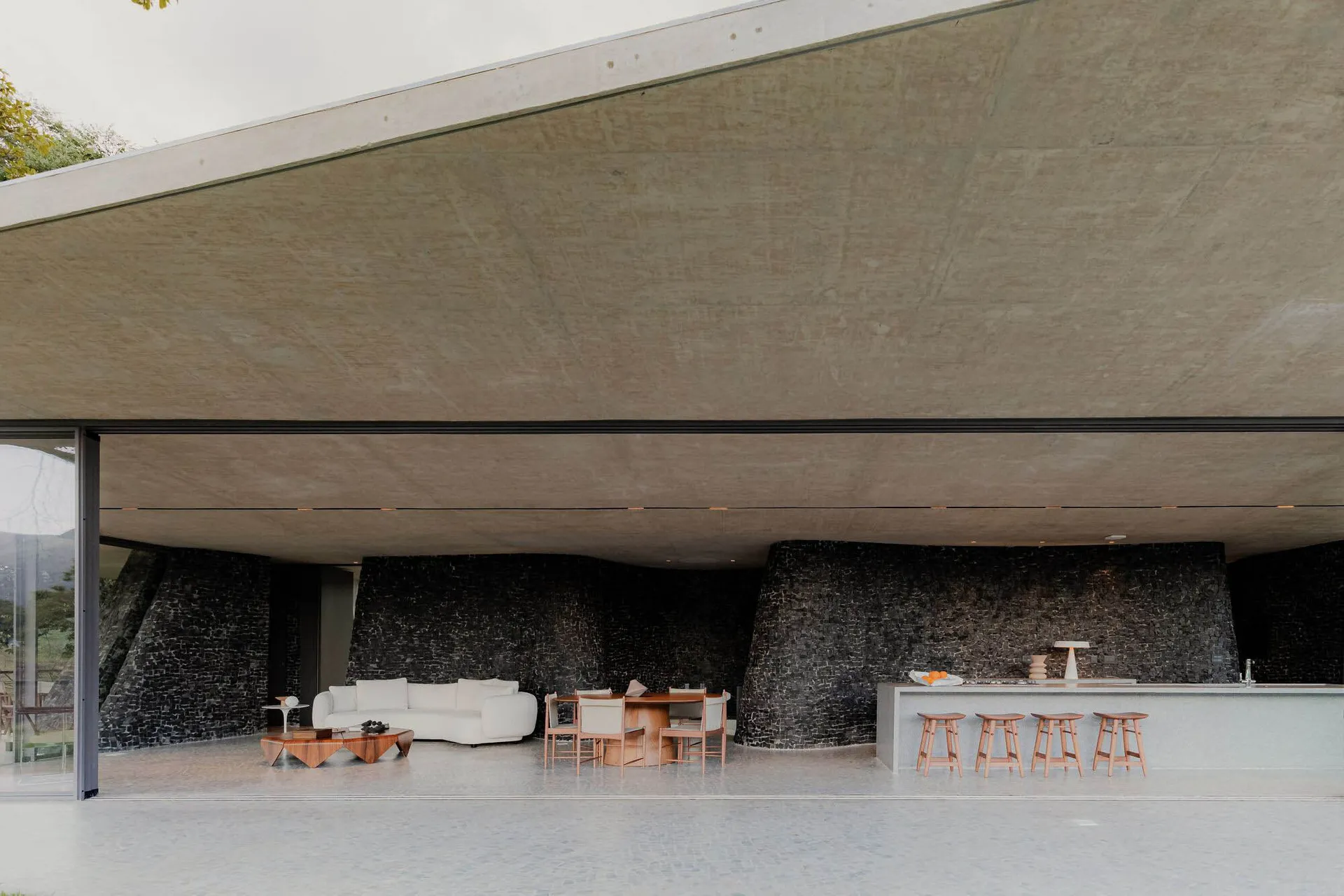 Modern living, kitchen, and dining space featuring concrete and stone materials.