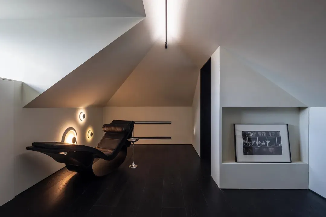 Modern minimalist living room featuring a wooden floor and black lounge chair.