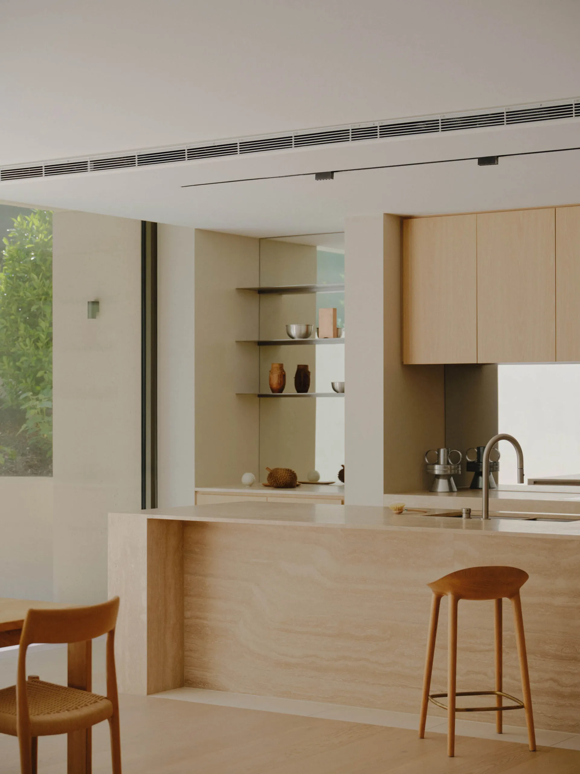 A minimalist residential kitchen featuring a natural stone countertop with a modern sink and minimalist cabinetry.