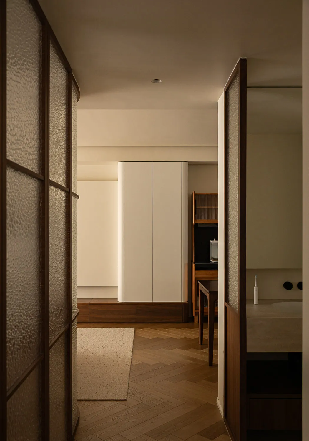 Modern minimalist bedroom featuring light-colored wooden floors, brass accents, and white cabinets.