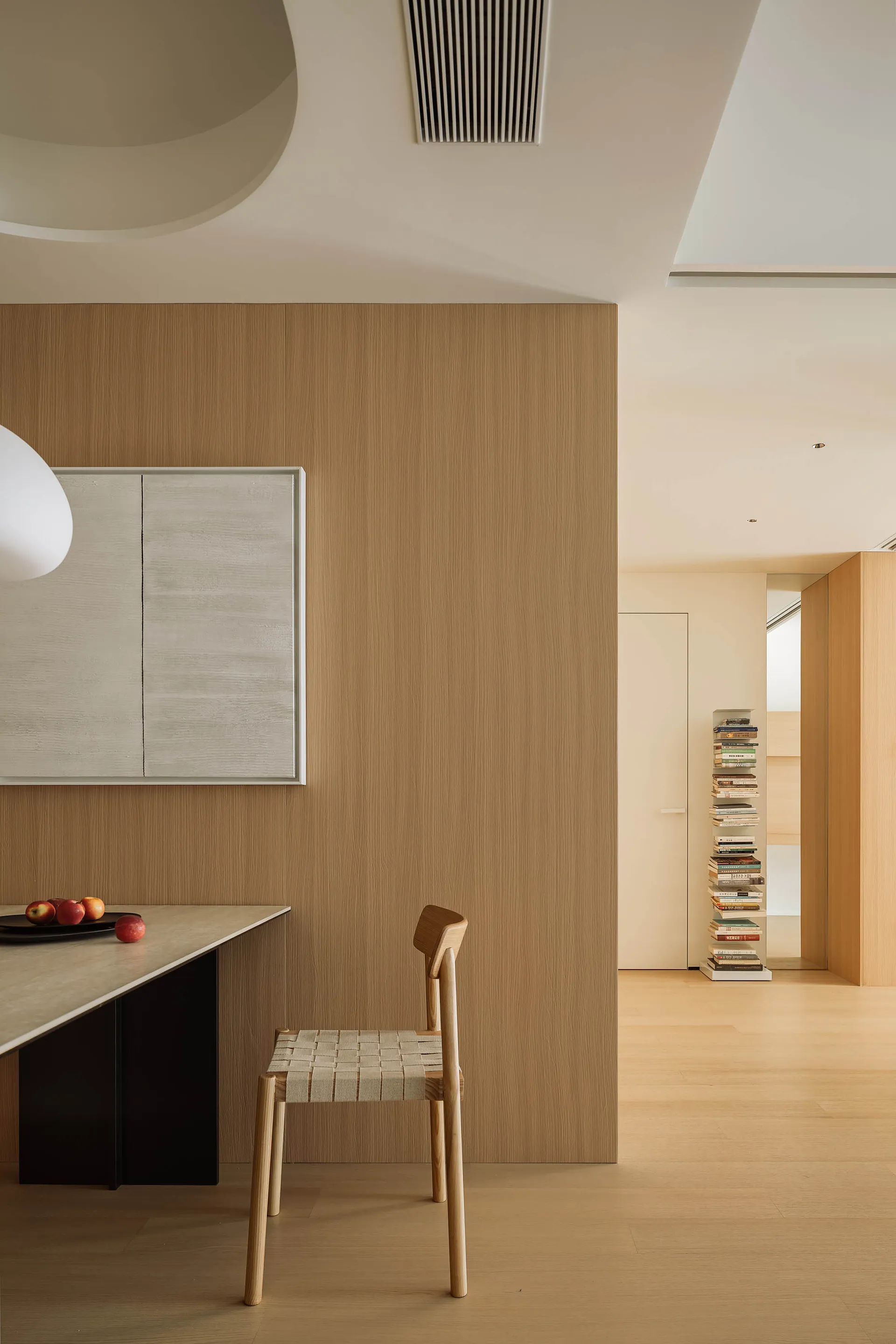 Modern minimalist dining room with a wooden table, chairs, and wall paneling.
