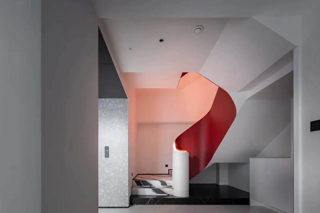 Modern staircase with red metallic wall, white flooring, and black-and-white striped carpet.