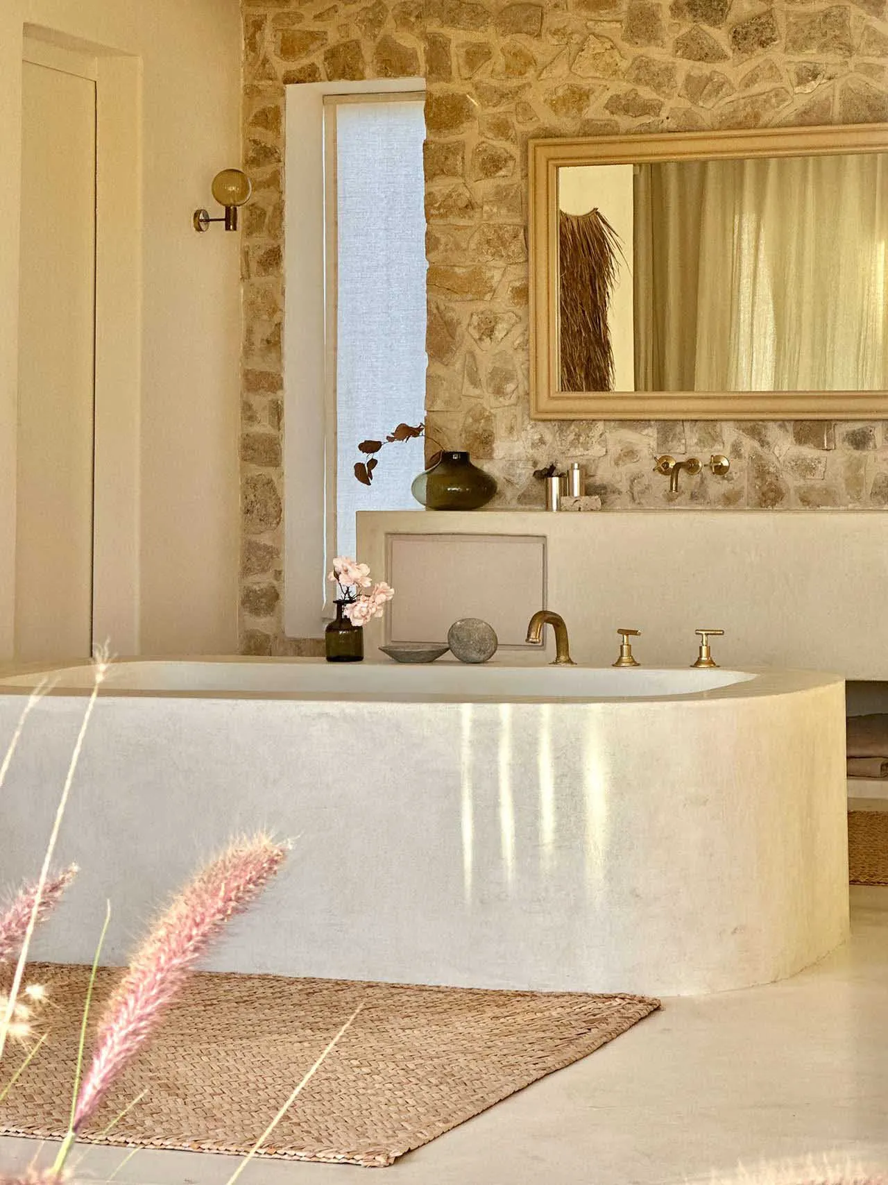 Modern minimalist bathroom featuring a concrete bathtub and stone wall