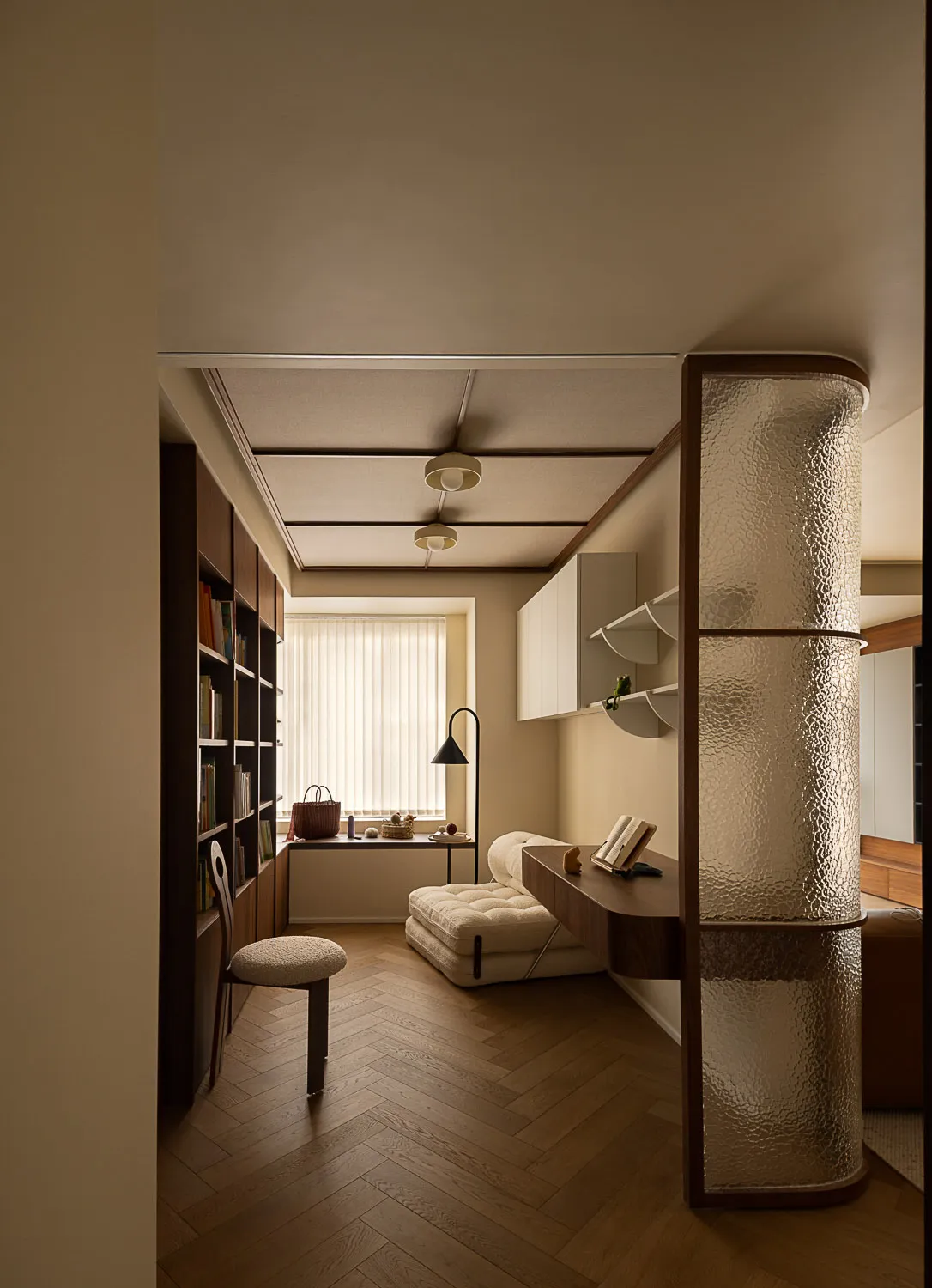 A minimalist living room featuring a wooden floor with a plush beige sofa and a floating desk.