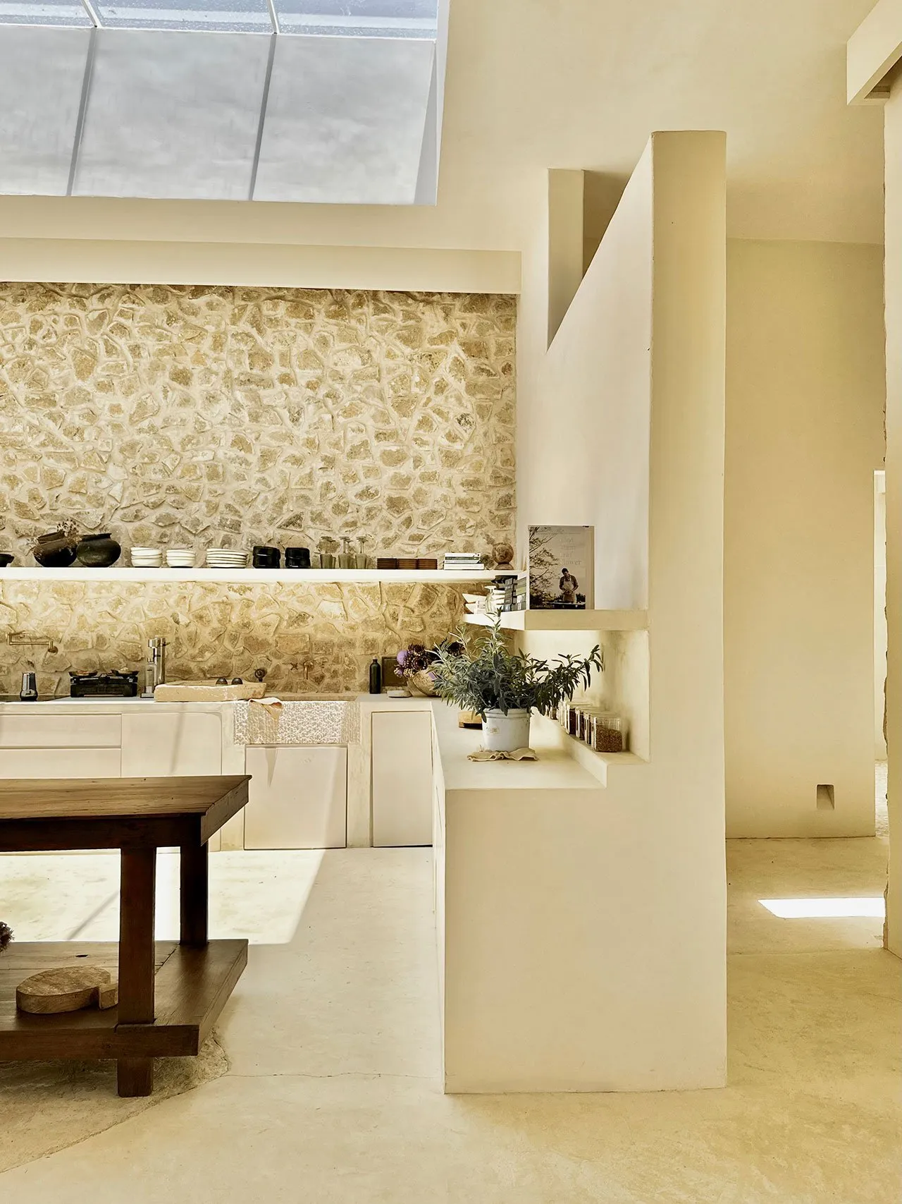 A minimalist residential interior with a concrete floor and stone walls.