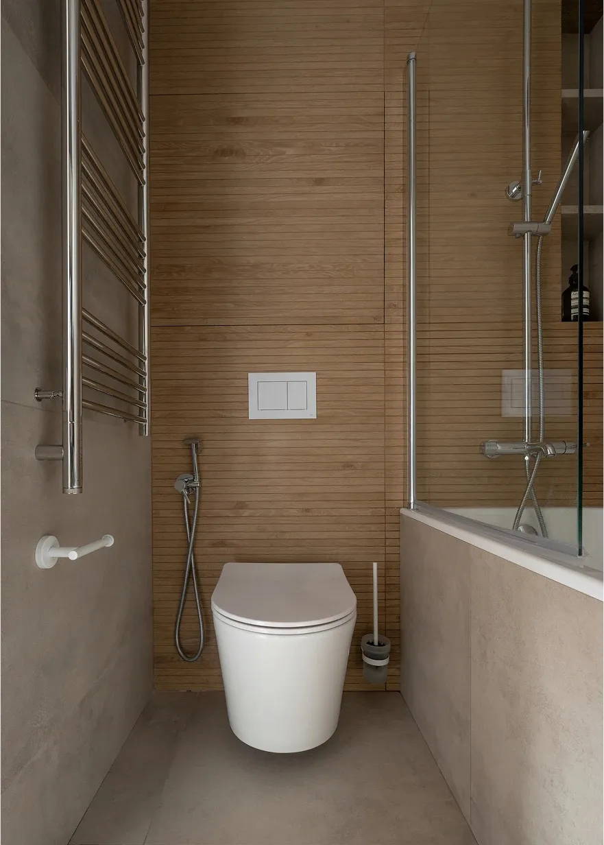 A modern bathroom features wood laminate tiles, a white toilet, and a glass shower enclosure.