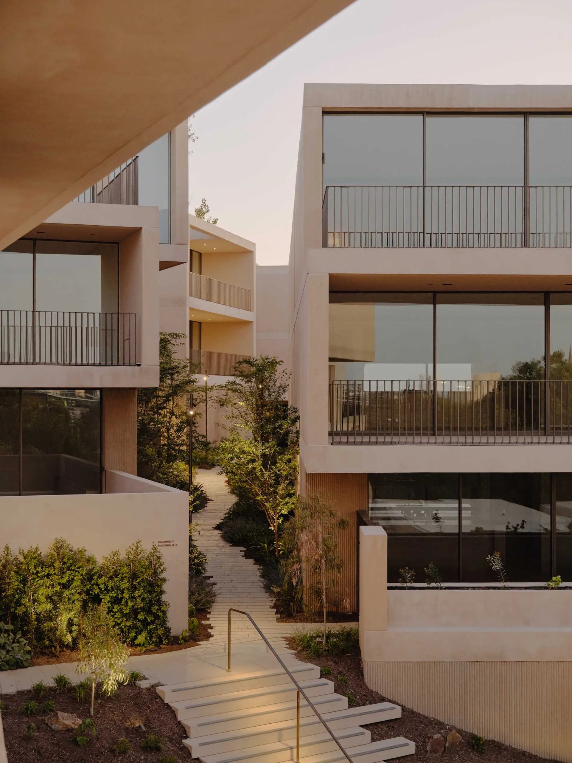 Modern residential apartments featuring concrete and glass exteriors with a serene garden view.