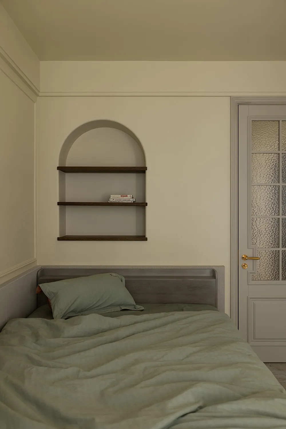 A minimalist bedroom with a bed, pillows, and a shelf.