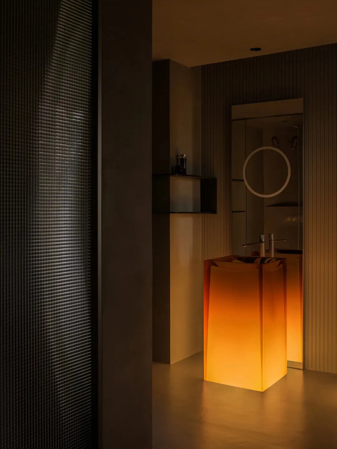 Modern bathroom with glass fixtures and illuminated orange lights.