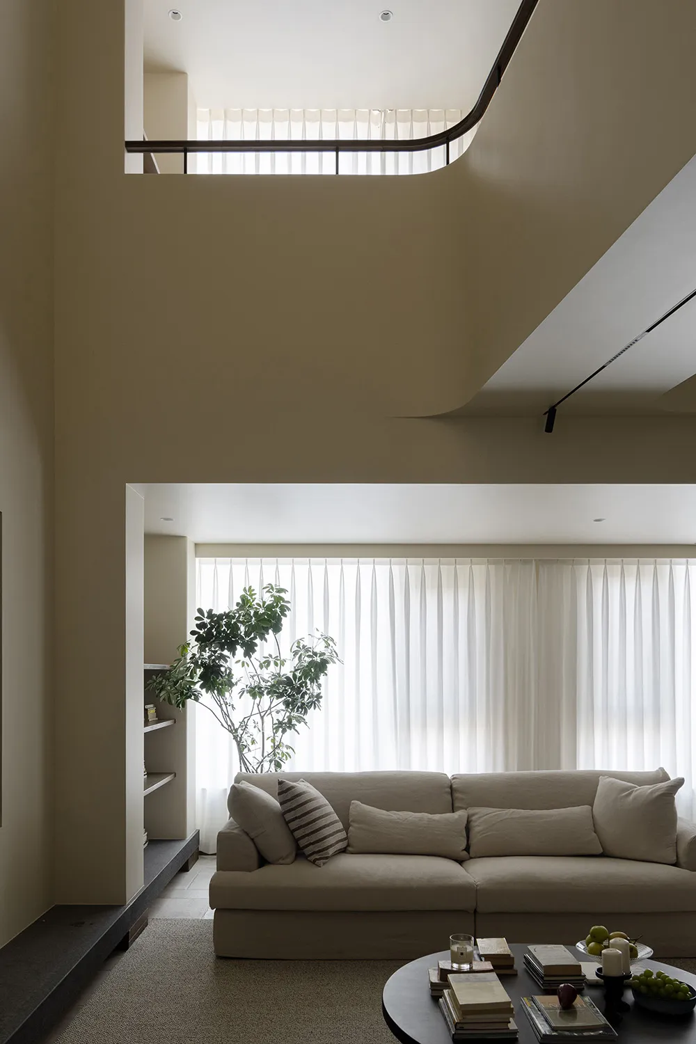 A modern living room featuring a comfortable fabric sofa with a minimalist design, natural light streaming in through large w