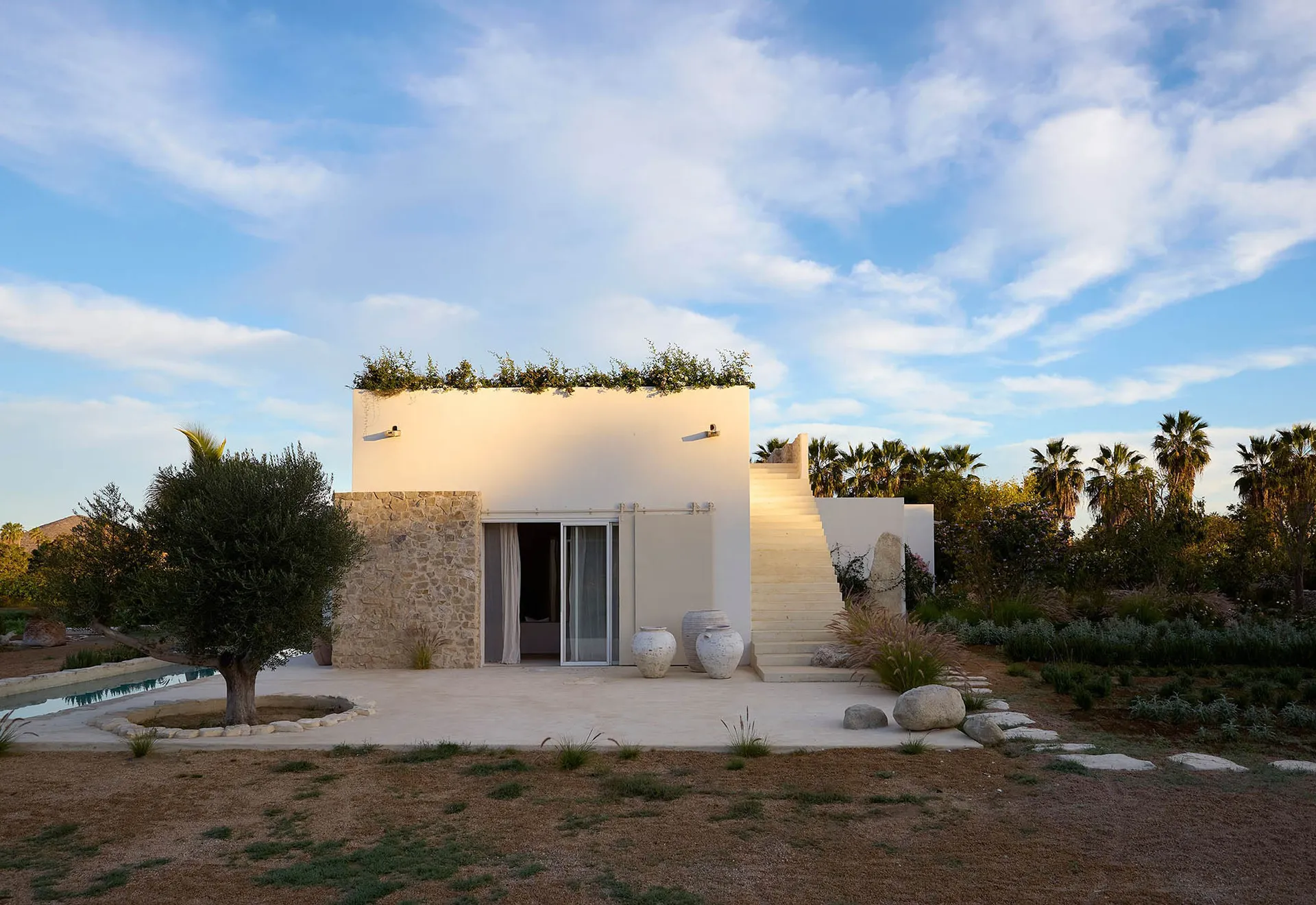 A modern residential exterior featuring white stucco and stone elements.