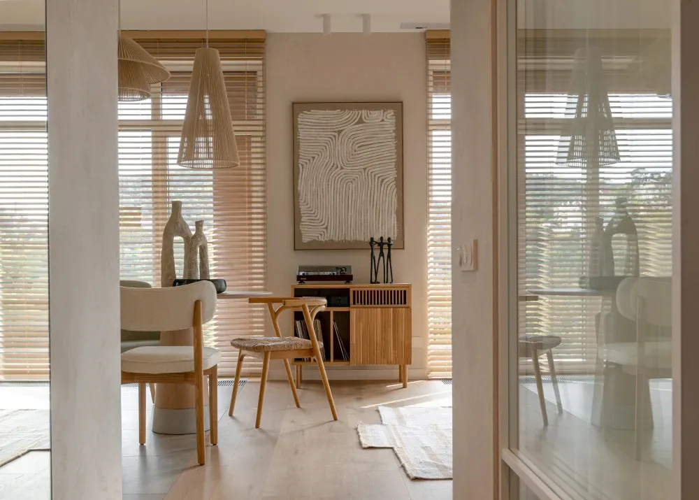 A minimalist dining room with wooden furniture and light-colored blinds.