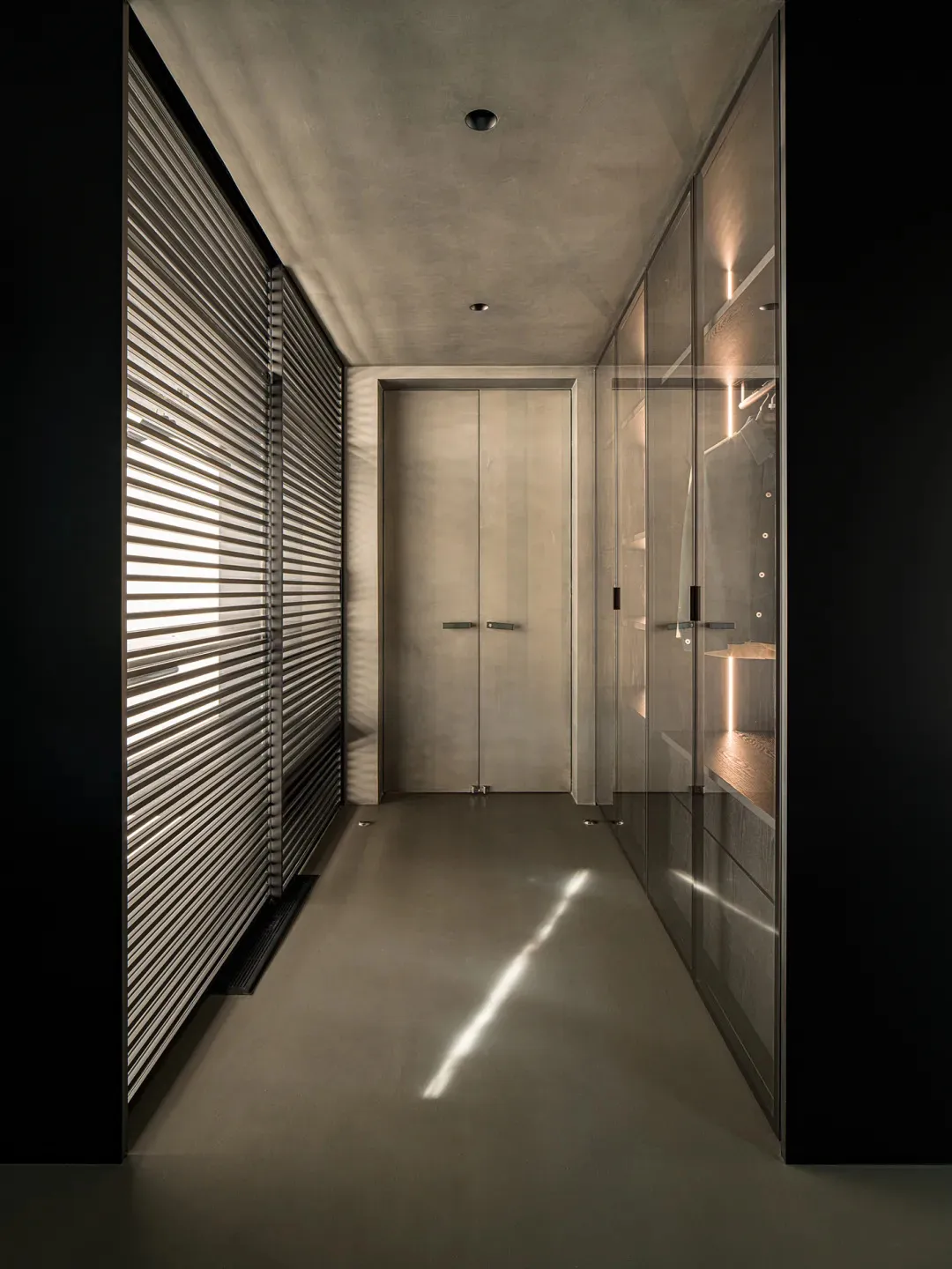 Modern closet with glass cabinets and concrete floor.