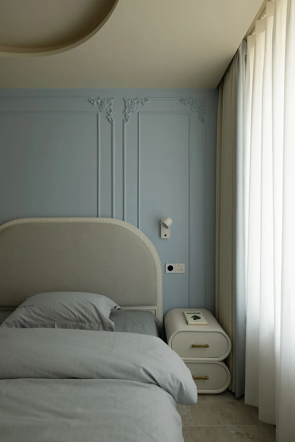 A modern minimalist bedroom with white bedding and plush fabric elements.
