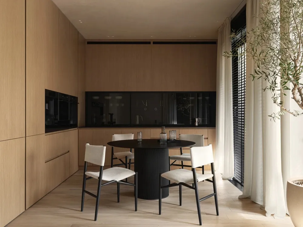 A modern residential kitchen featuring wooden cabinets, a black dining table, and white upholstered chairs.
