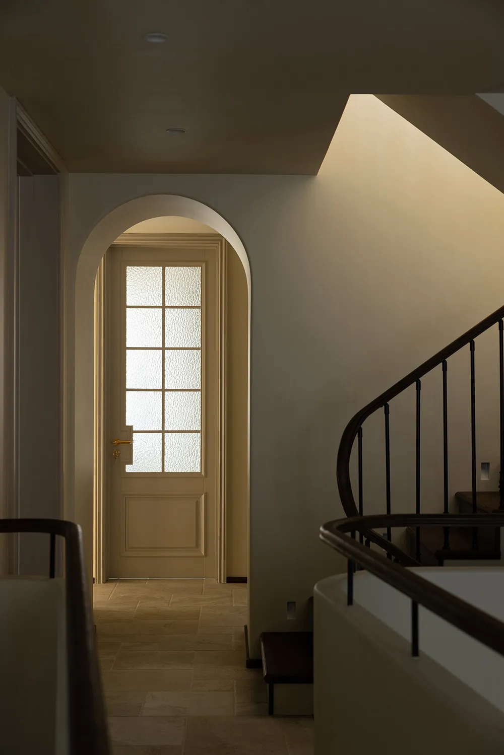 A cozy, warm-toned residential corridor with an arched doorway and soft lighting.