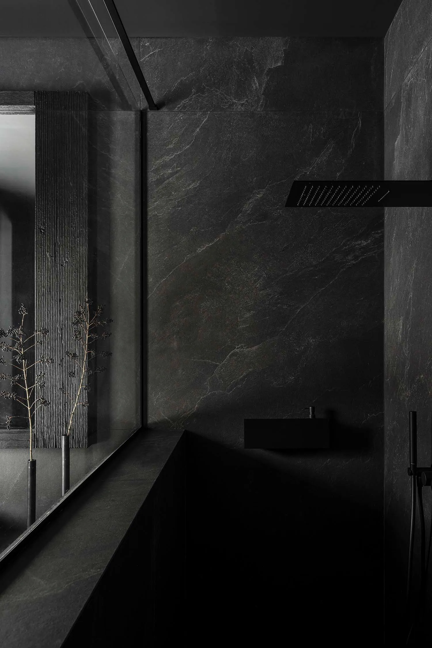 A modern bathroom with dark stone walls and minimalist design features.