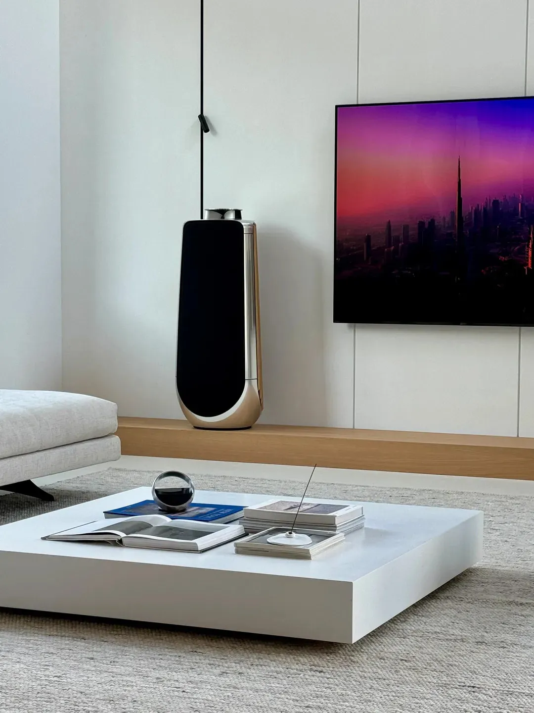 A modern minimalist living room featuring sleek, clean lines and a mix of white and wood materials.