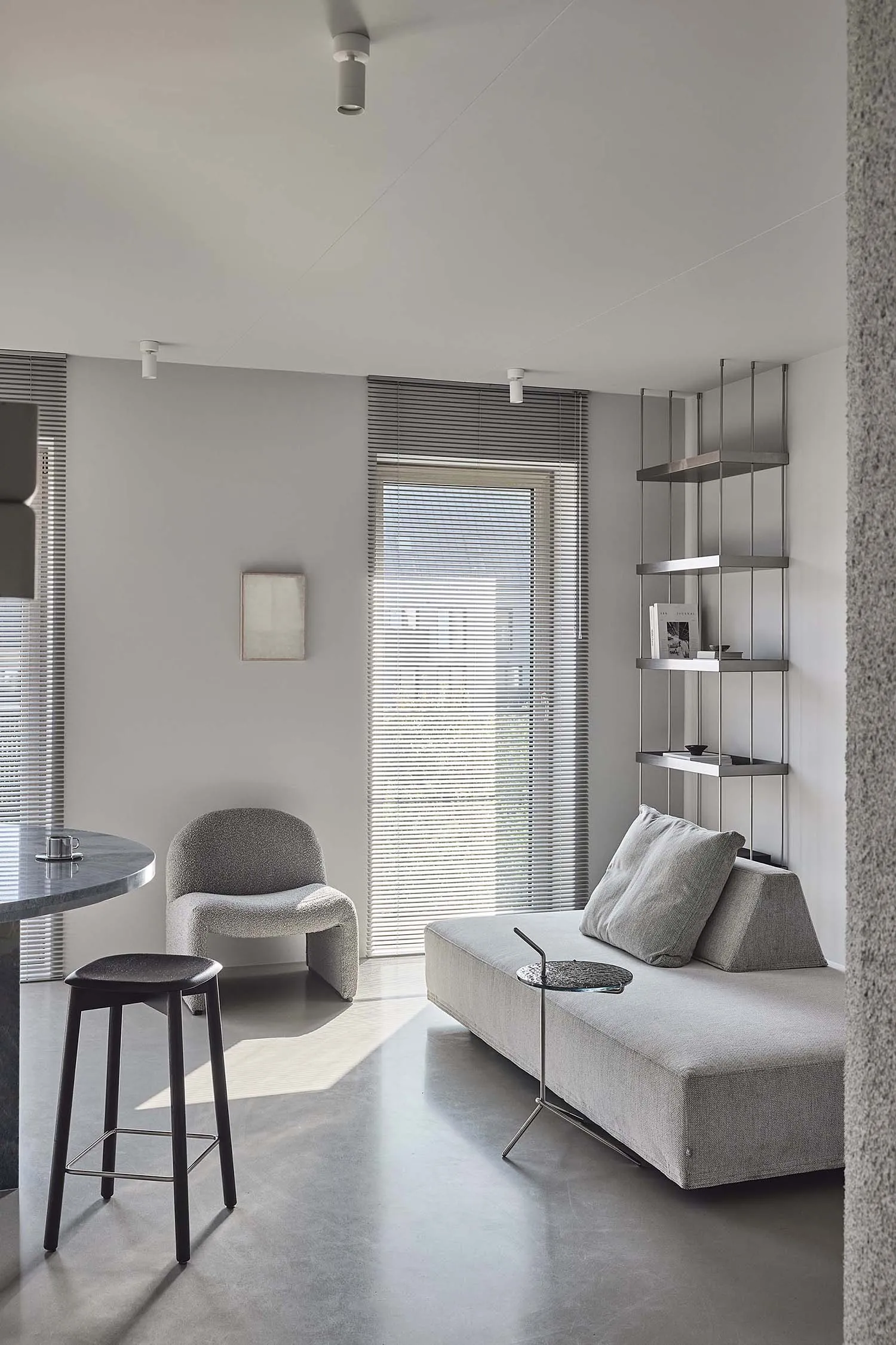 Modern living room with neutral-colored furniture and concrete flooring and walls.