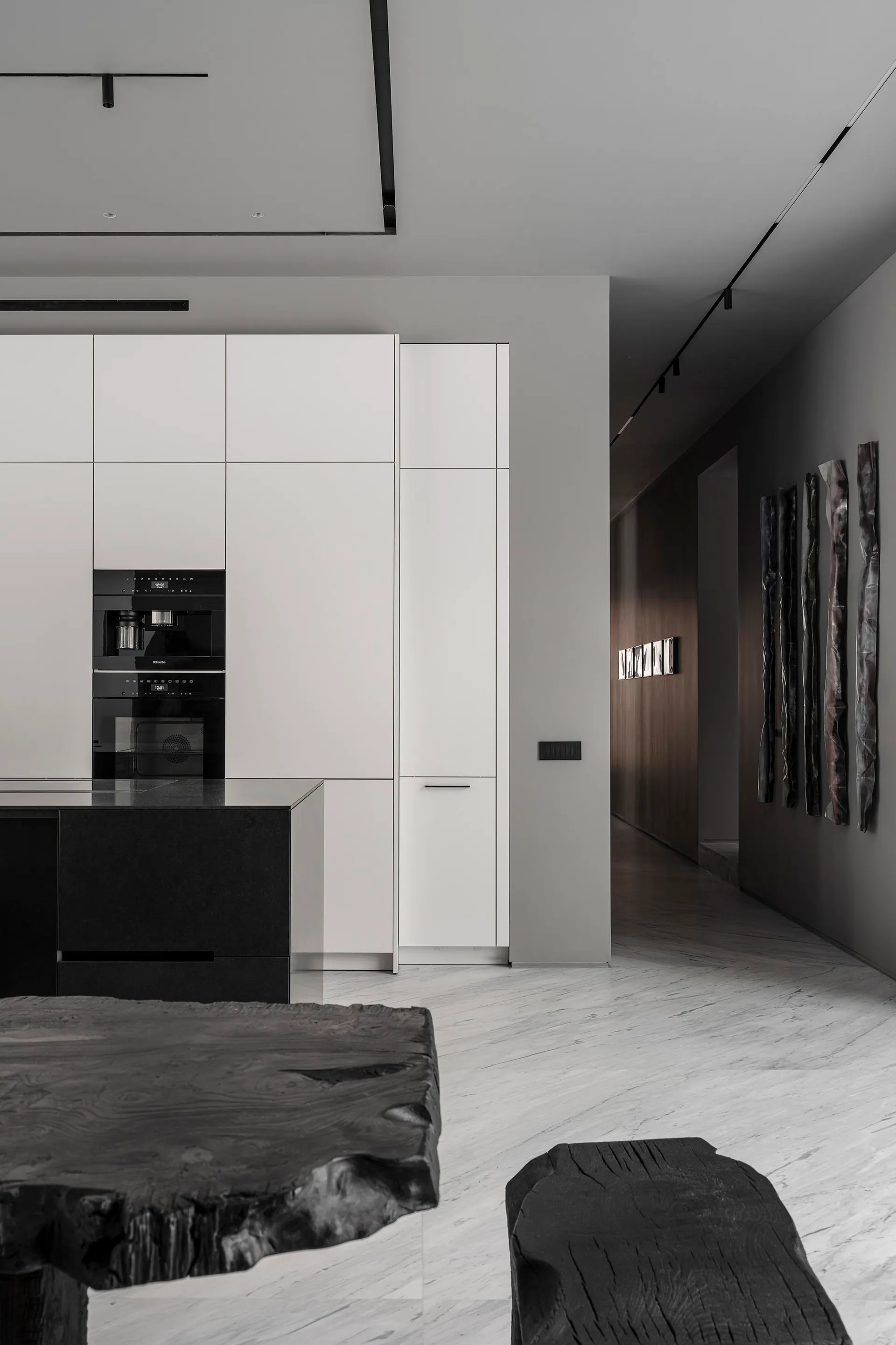 Modern white kitchen interior featuring minimalist black marble countertops and cabinets.