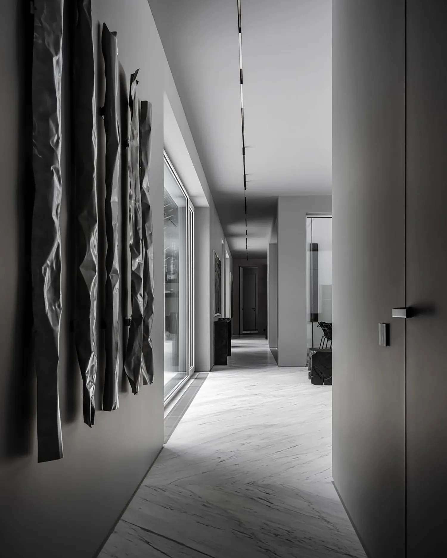 Modern industrial suite hallway featuring metallic ribbons hanging from the ceiling and linear lighting fixtures.