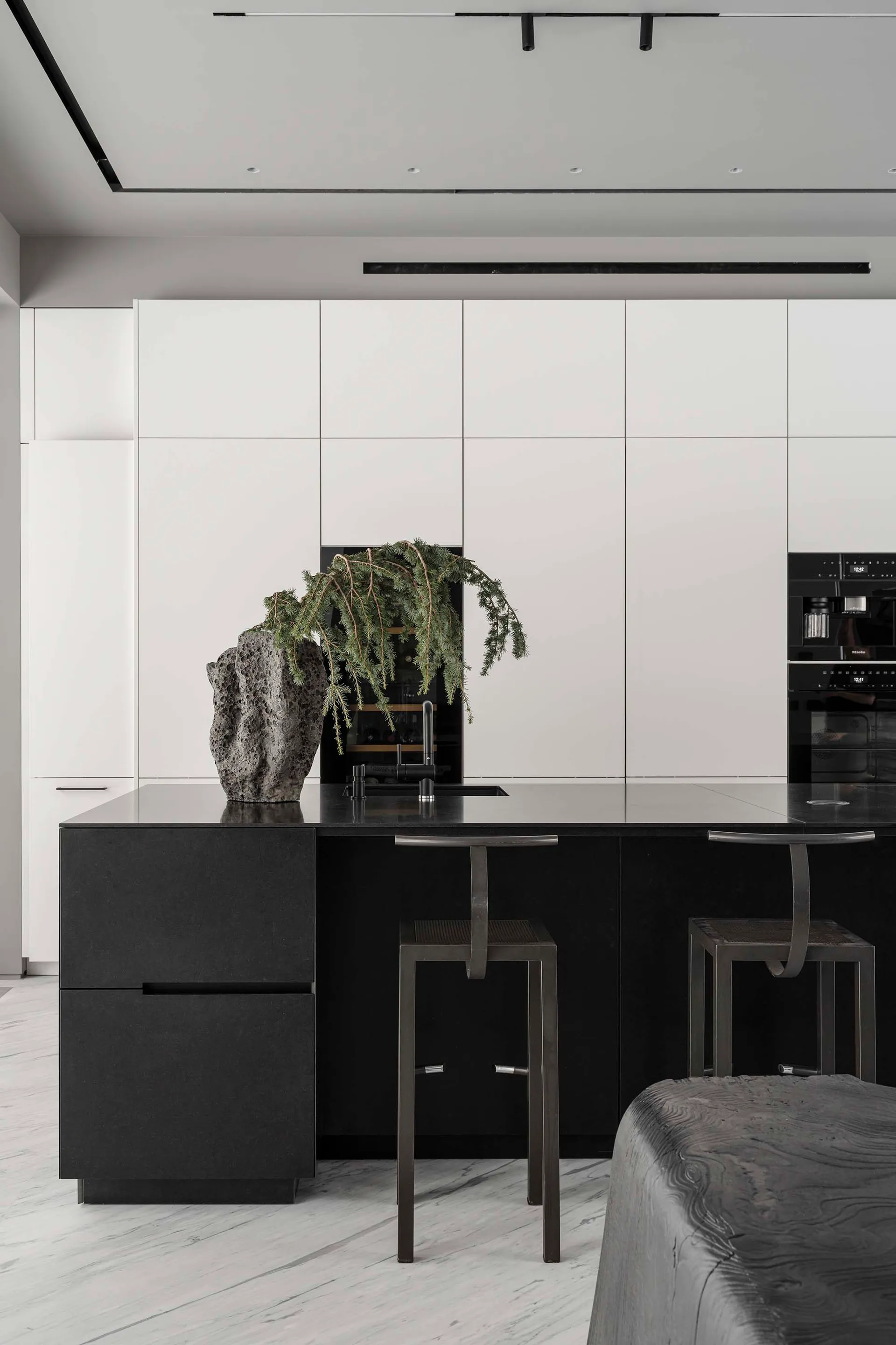Modern kitchen with black and white interior, featuring a minimalist island with black countertops, white walls, and modern a