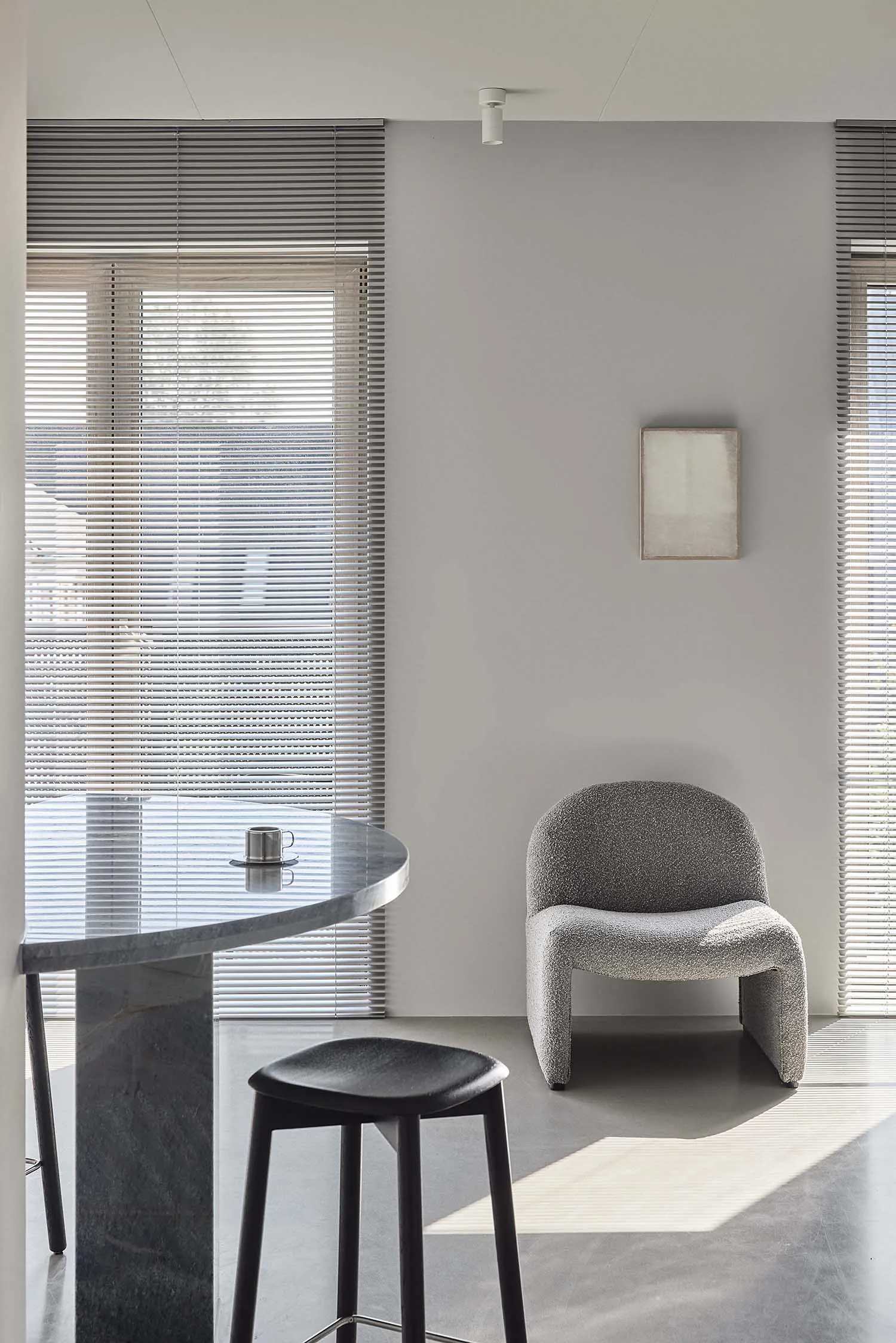 A minimalist modern kitchen with a marble countertop, stool, and round table.
