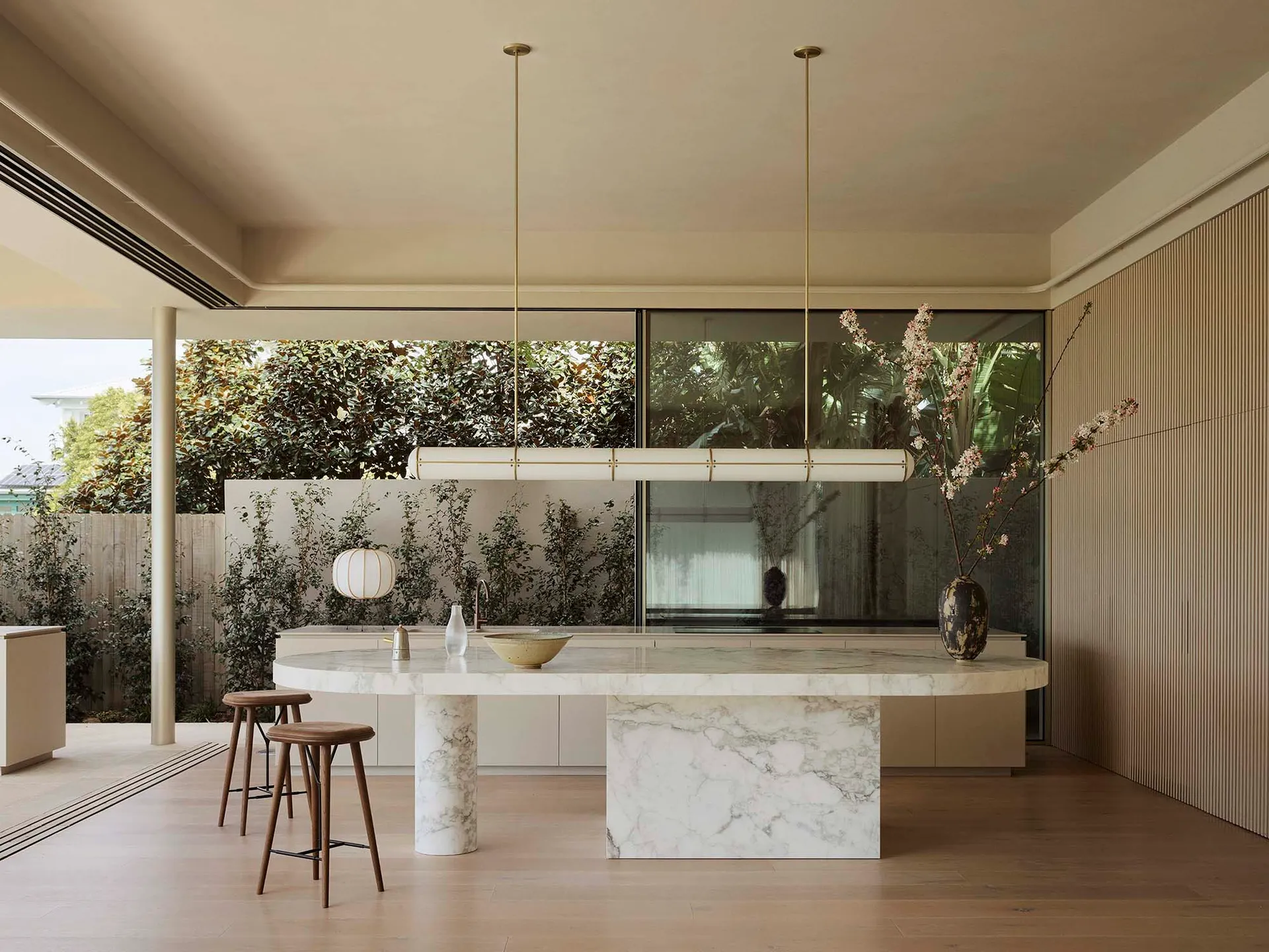 Modern kitchen interior featuring a marble countertop and island, with a minimalist aesthetic and large windows.