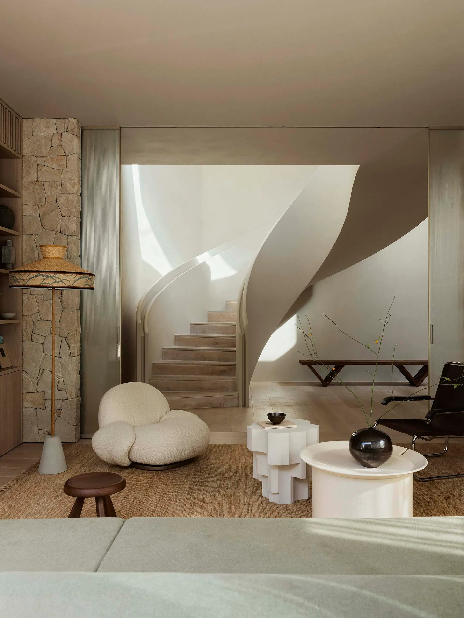 A modern living room with a unique curved staircase, minimalist furniture, and contemporary design elements.