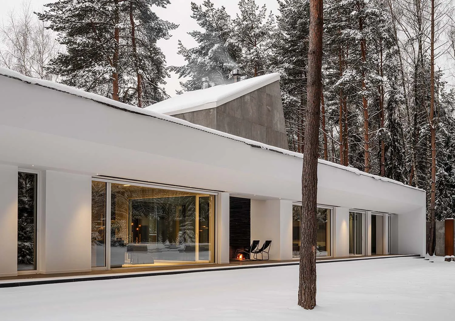 Modern minimalist house with concrete and glass materials and a snowy exterior