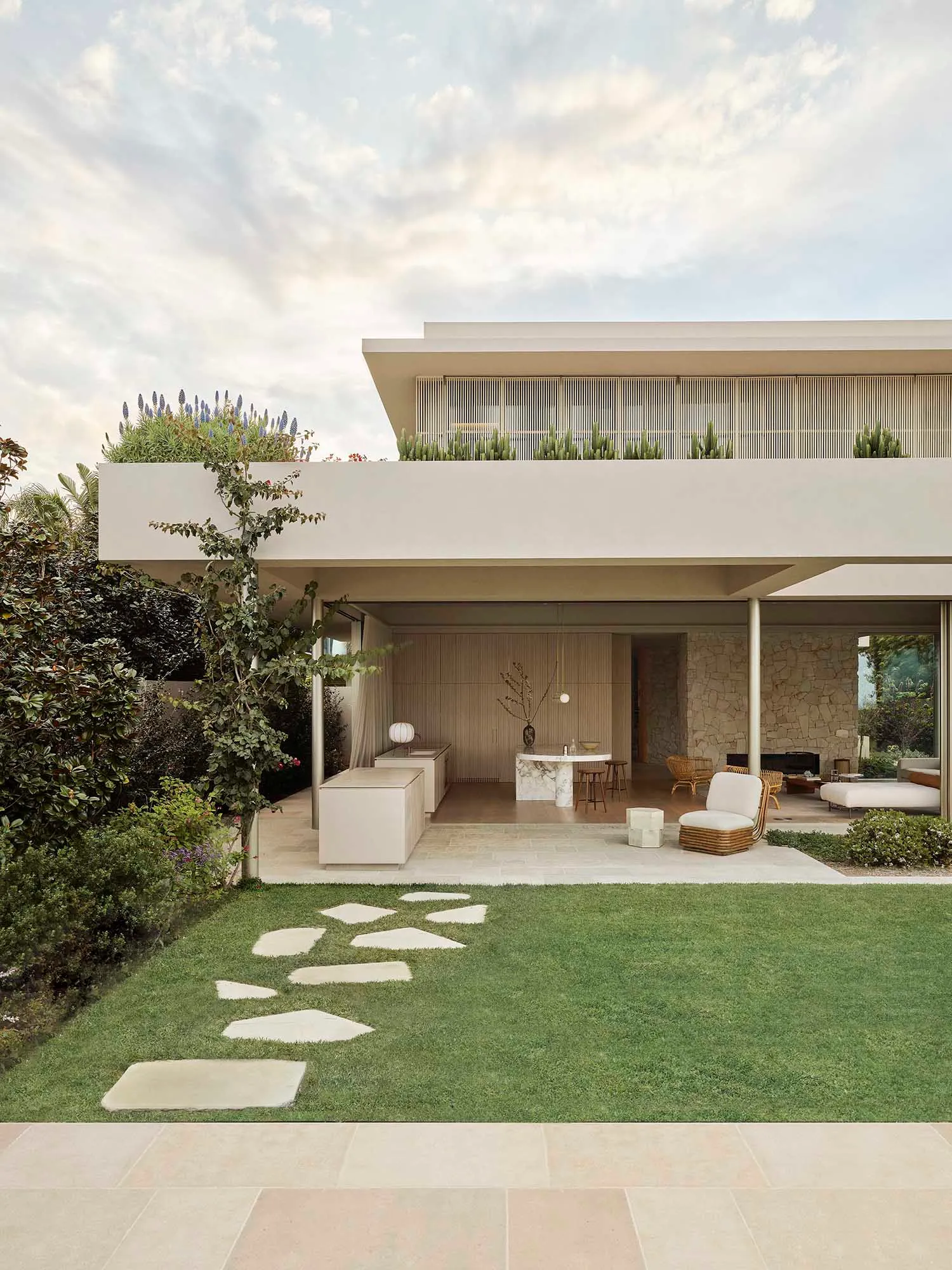 Modern residential home exterior with sandstone facade and rooftop garden.