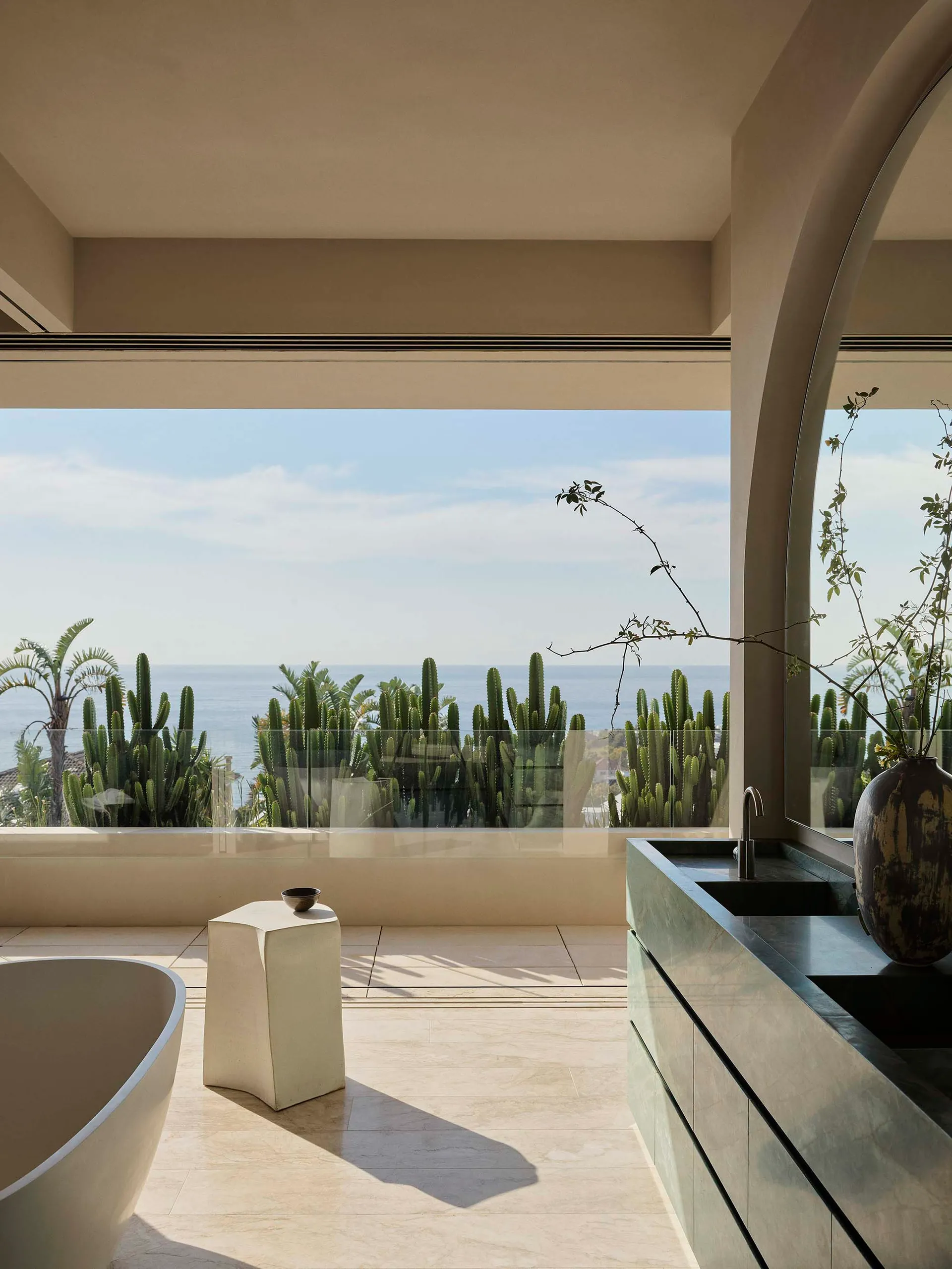 Modern minimalist bathroom featuring marble countertops, concrete walls, and ceramic tiling with a view of the ocean.