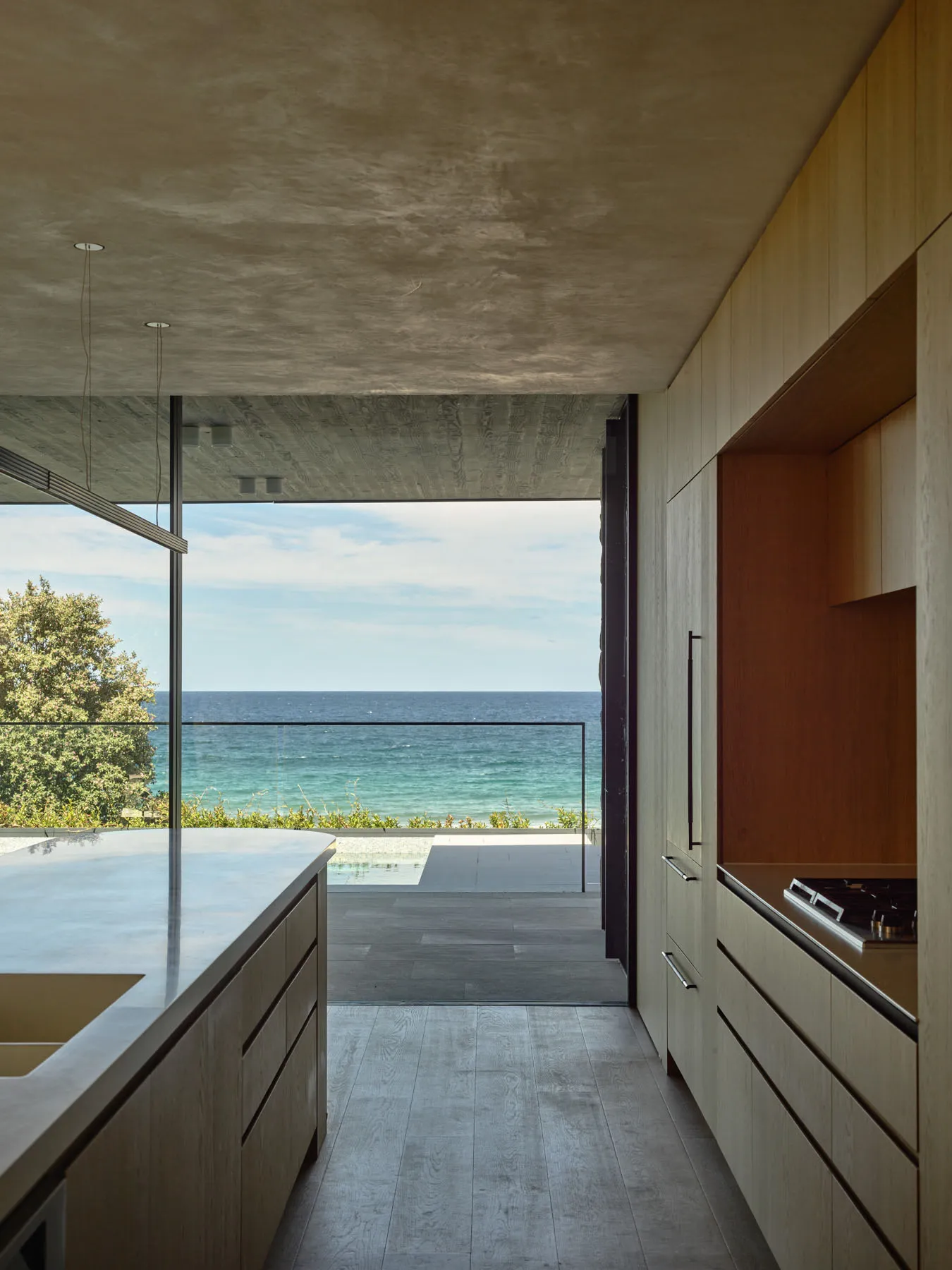 A modern residential kitchen with wooden elements and a view of the ocean.