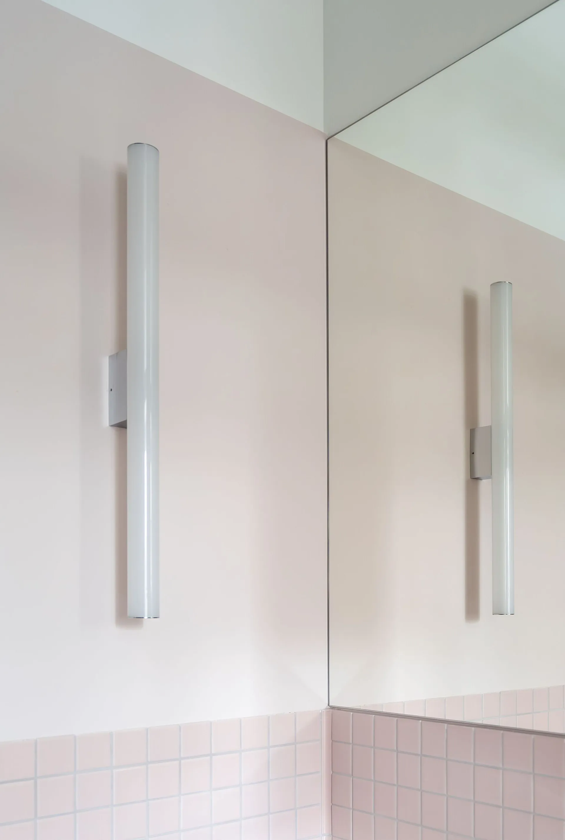Minimalist bathroom with pink tiles and white tube lights.