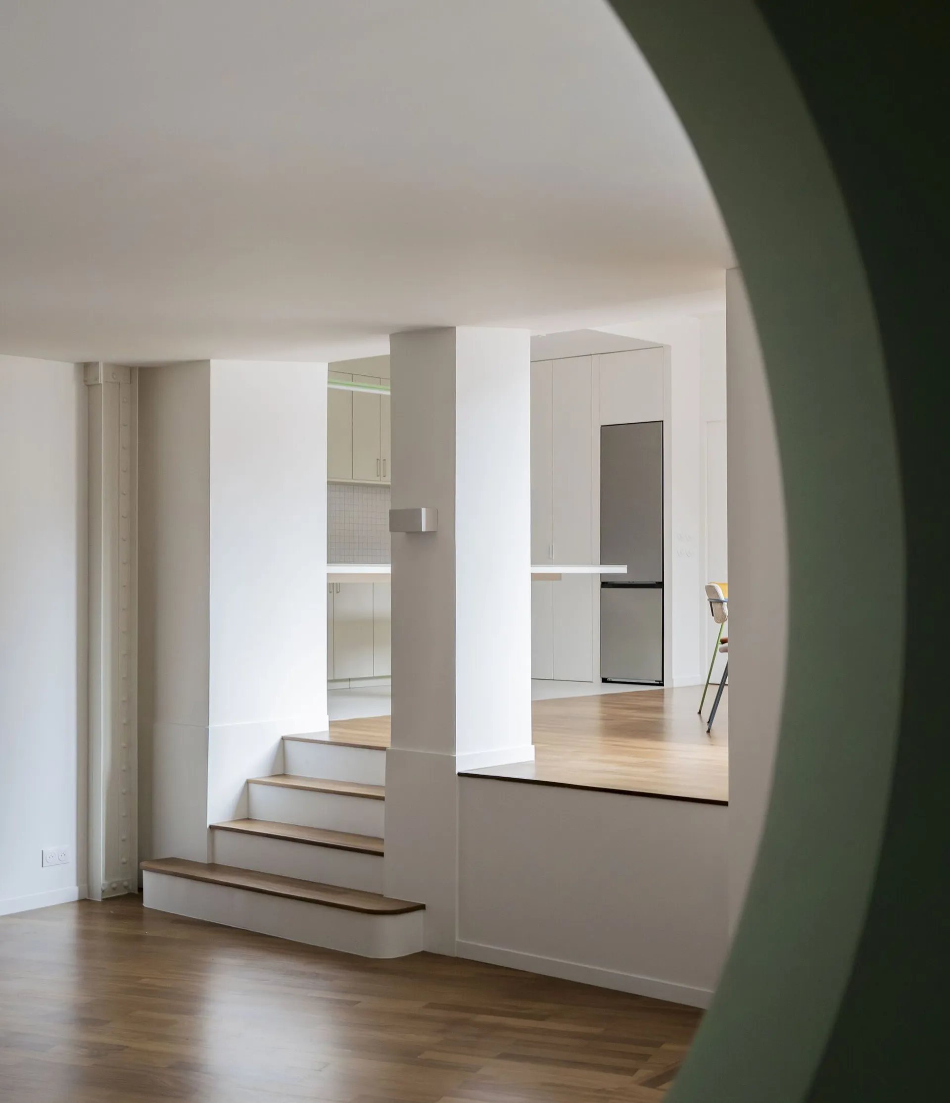 Modern minimalist living room with white walls and wooden stairs