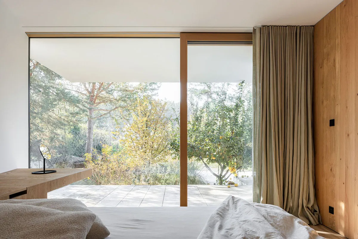 Modern bedroom with wooden furniture and a view of a garden.