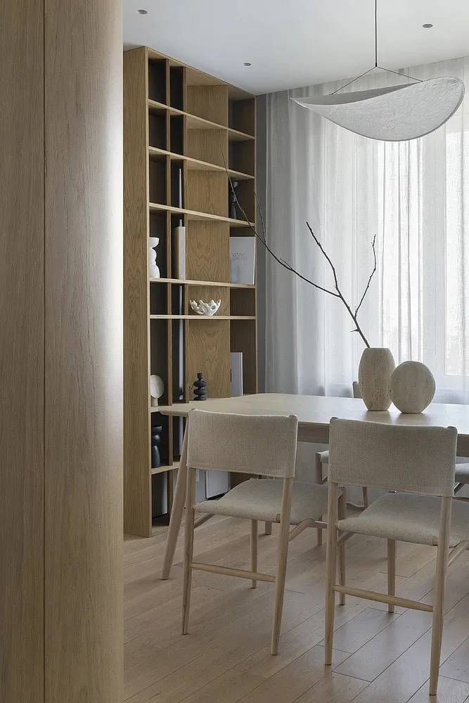 Modern dining room featuring wooden furniture, white curtains, and minimalist decor.