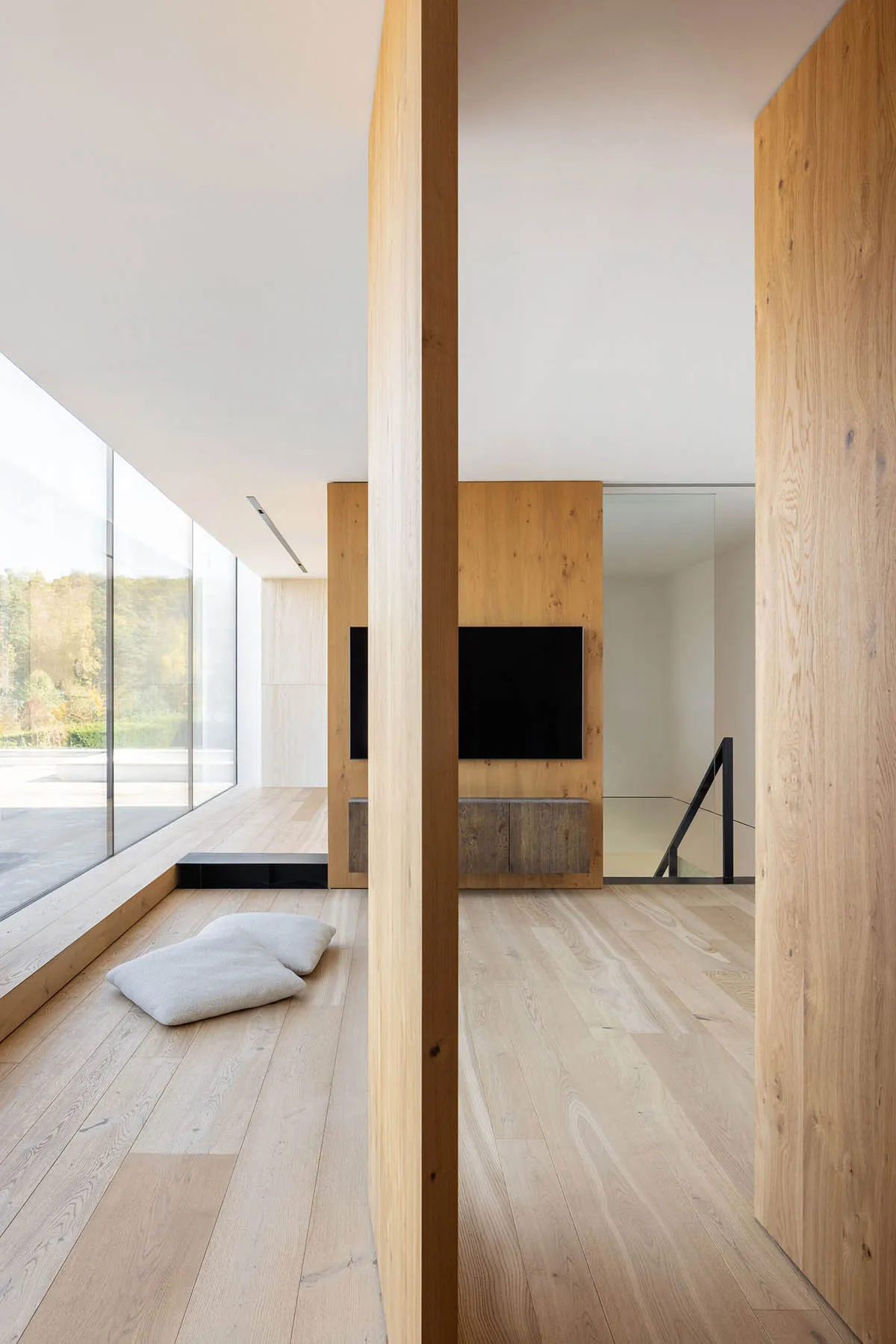 A modern minimalist living room with wooden walls and a television mounted on the wall.