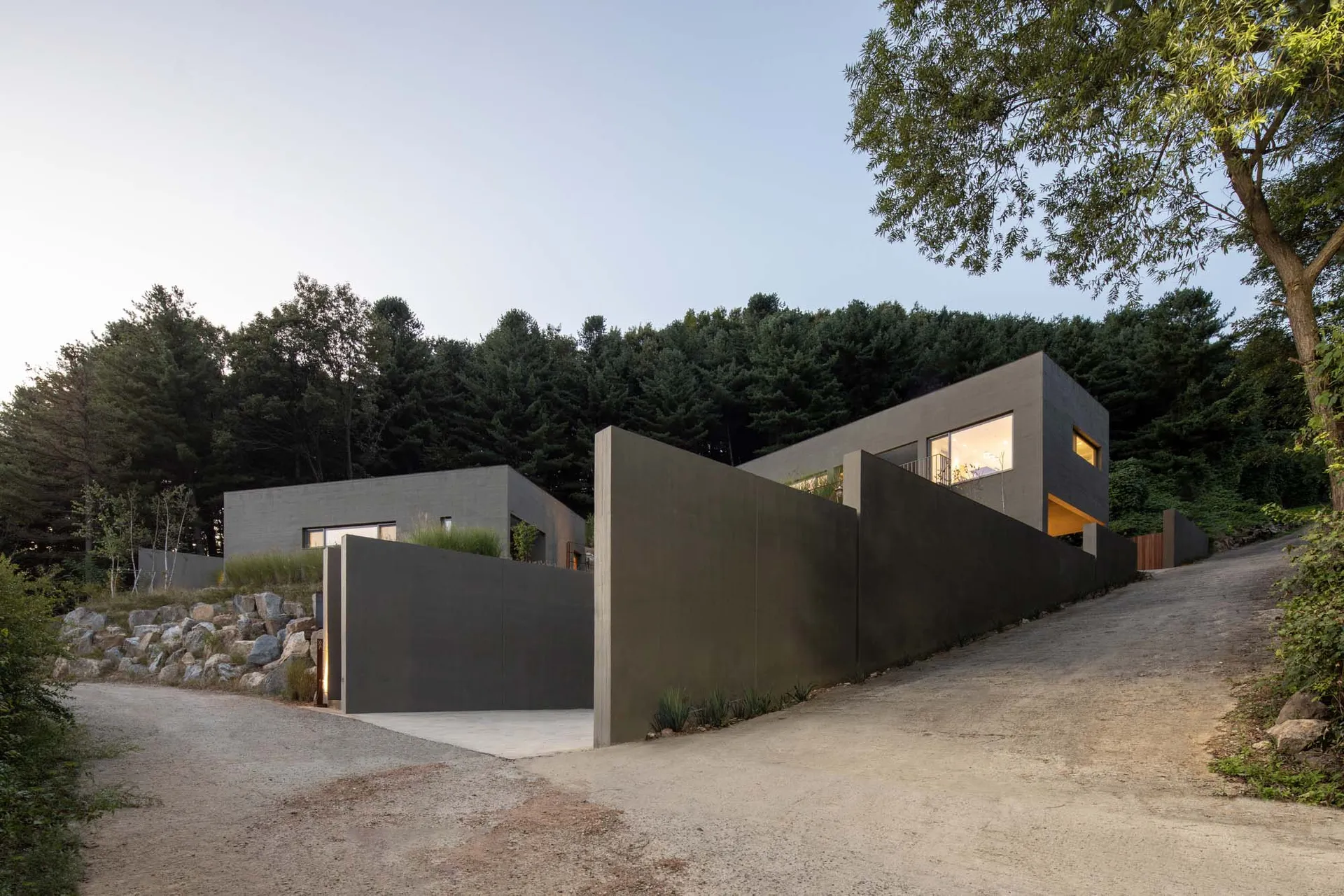 Modern residential house with minimalist design, featuring concrete exterior and large windows.