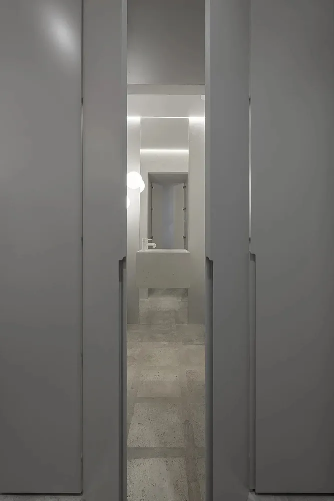 極簡浴室,配有現代混凝土洗手台與地板,以及小型鏡子和燈具。